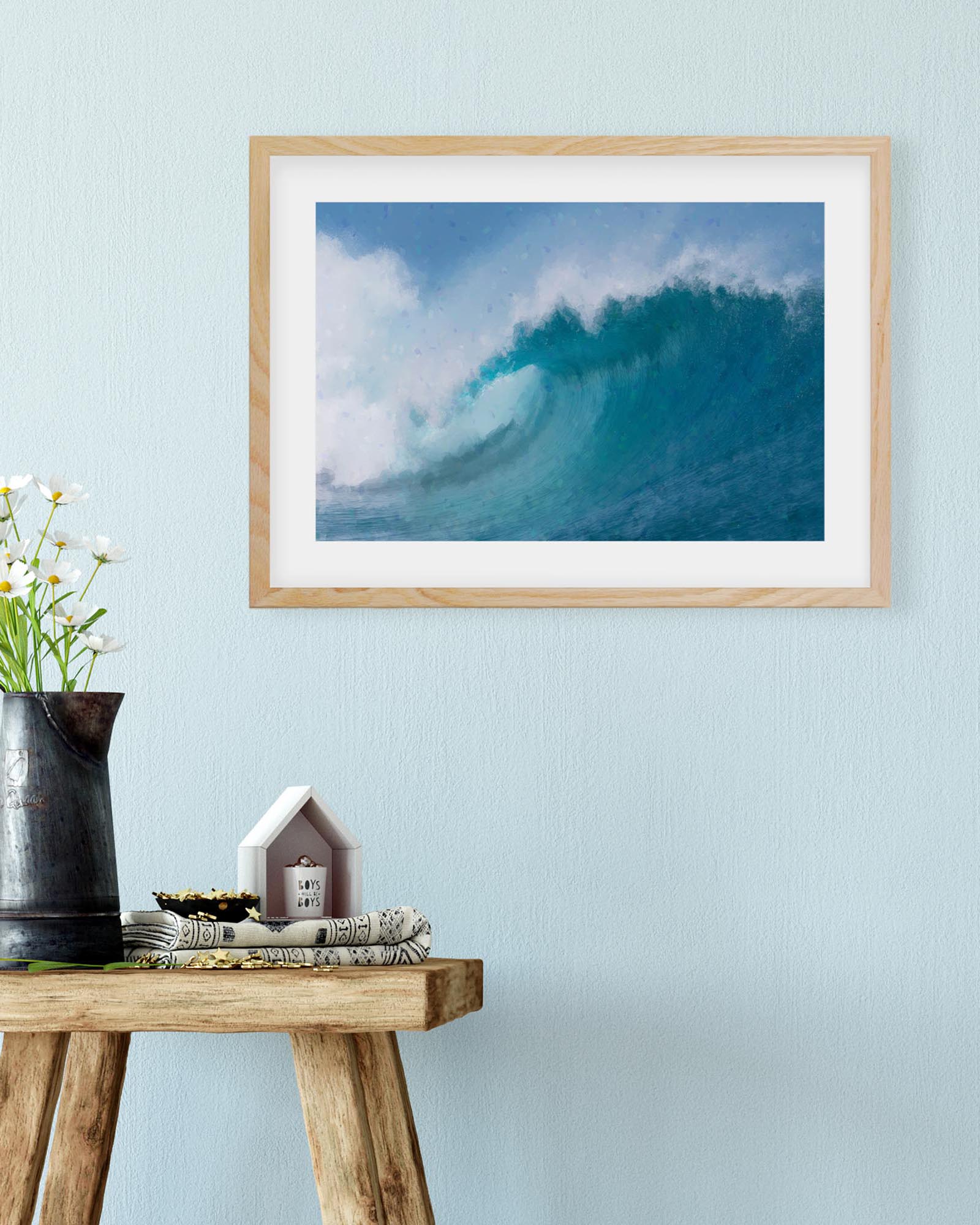 Framed artwork of a blue wave on a light blue wall above a wooden table with decorative items.