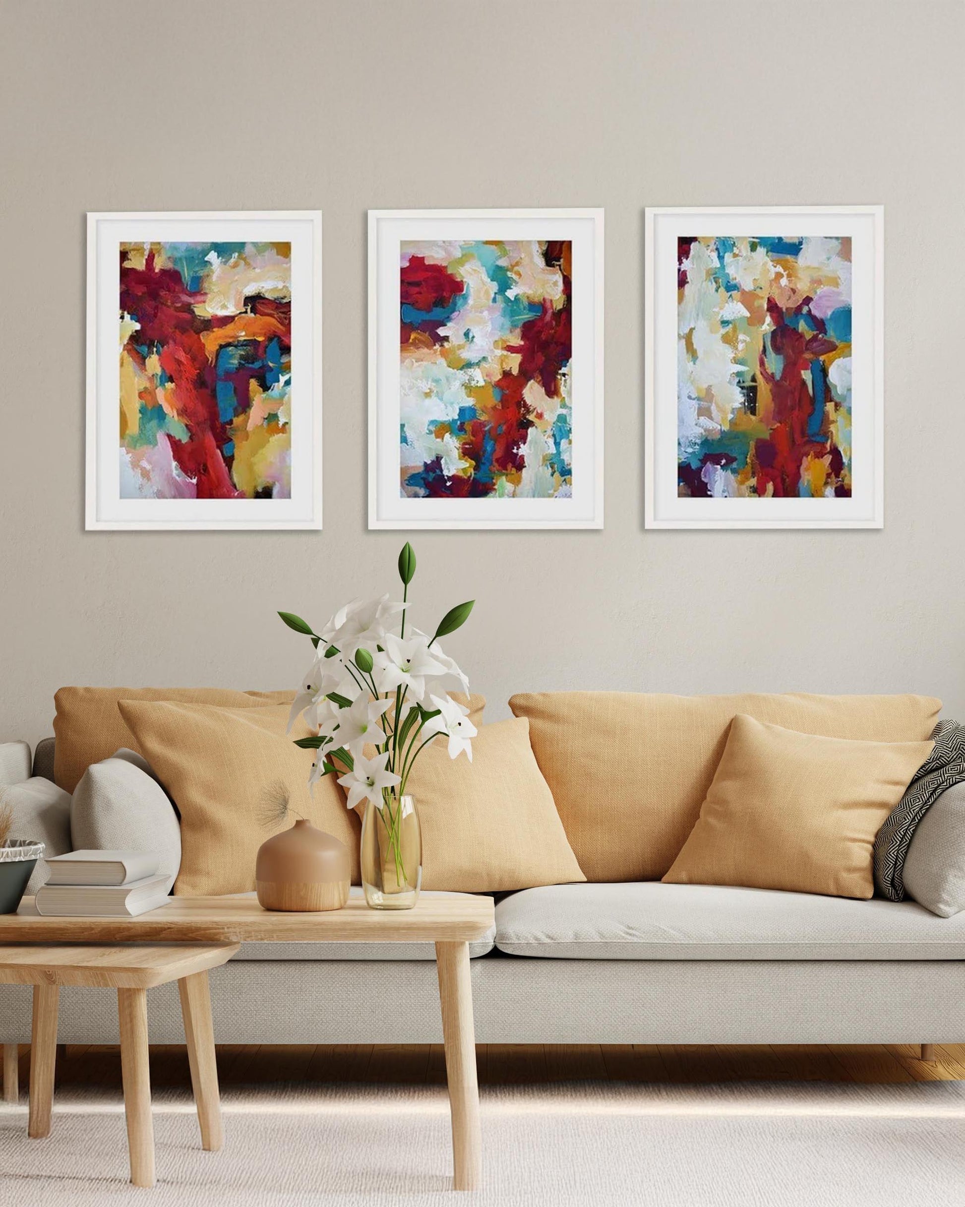 A set of three framed abstract art prints hanging on a wall over a beige sofa in a living room setting.