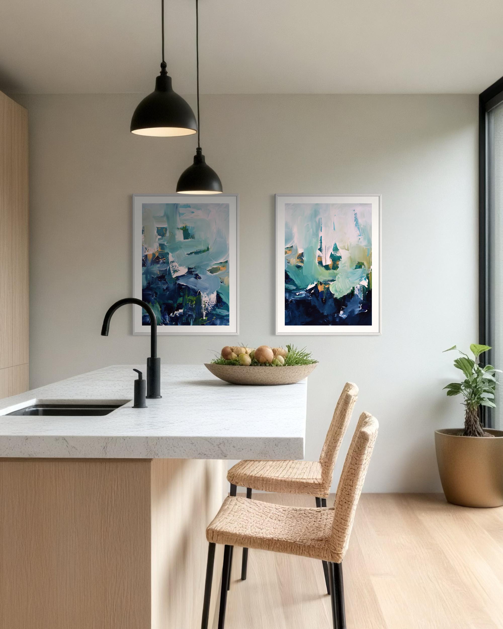 Modern kitchen with abstract art on the wall, a bowl of fruit on the counter, and wicker chairs.