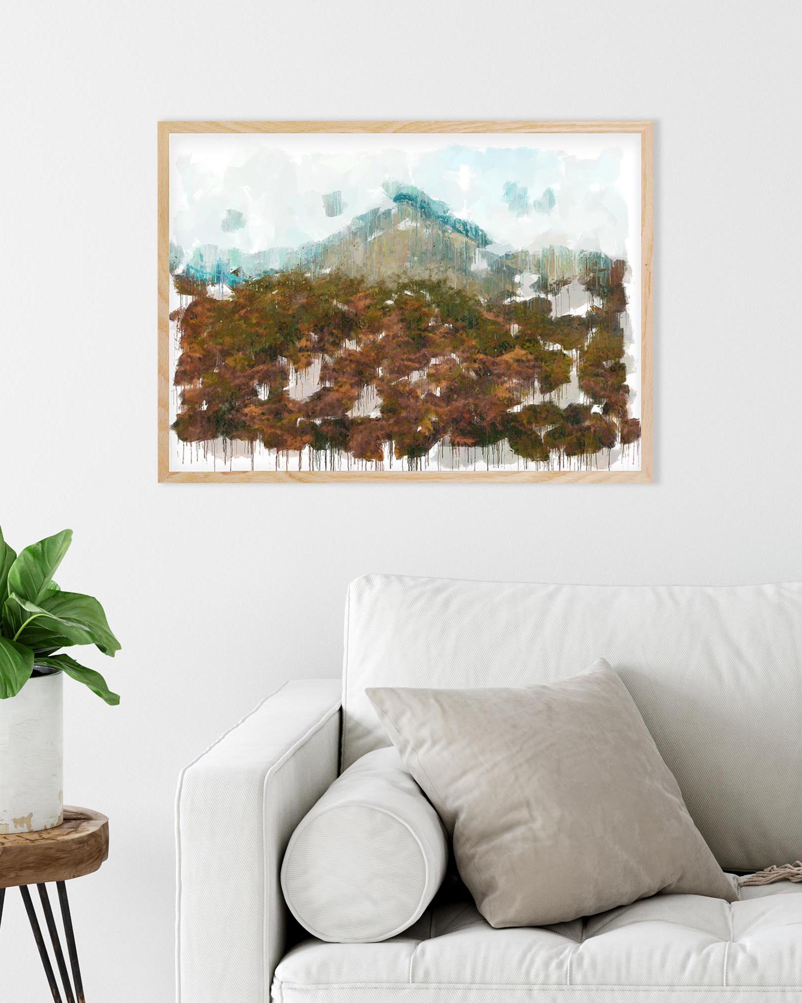 Framed nature print of a forest scene above a white sofa in a living room.