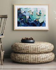 Woven ottoman with decorative items in a room with abstract art on the wall.