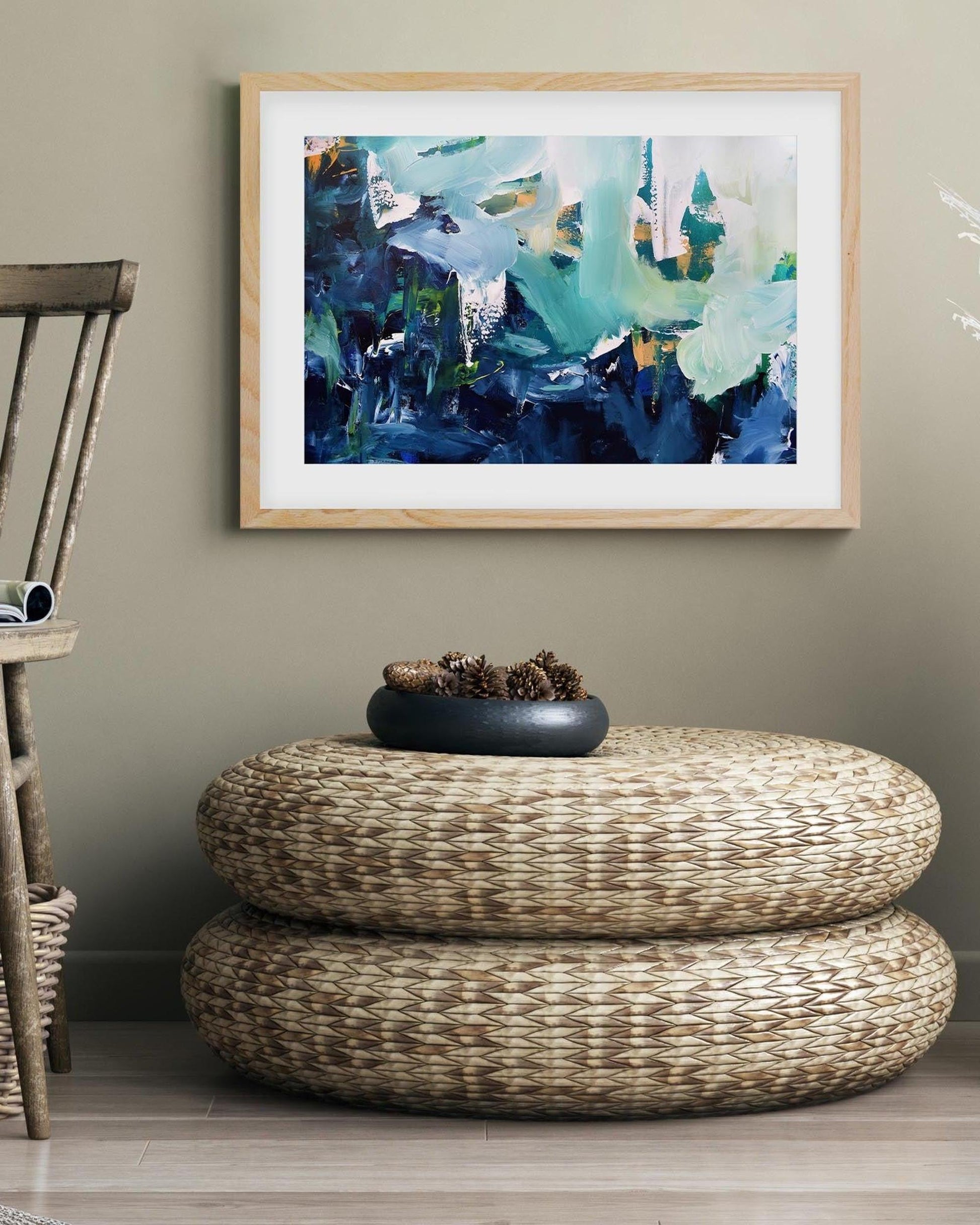 Woven ottoman with decorative items in a room with abstract art on the wall.