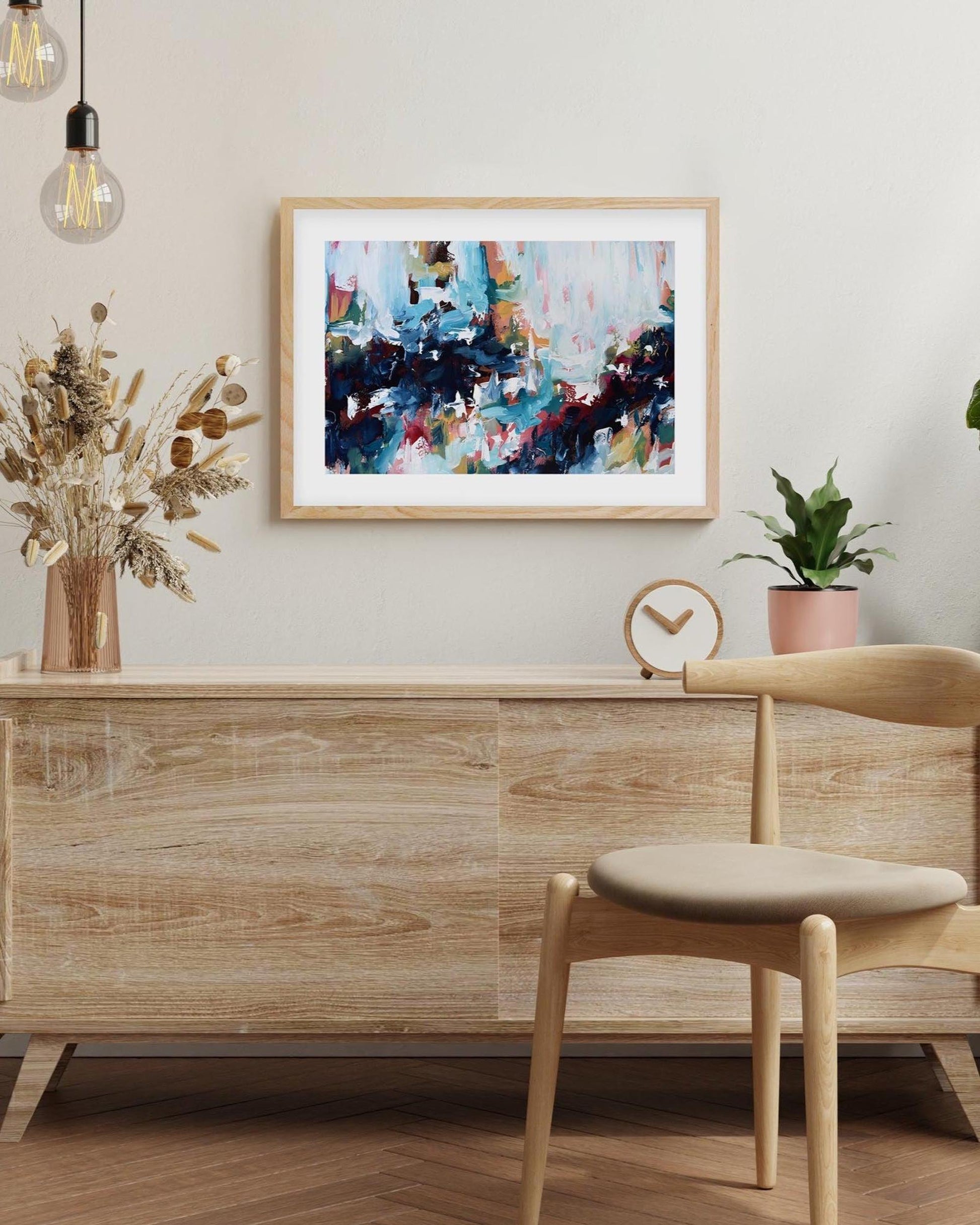 Modern interior with wooden sideboard, chair, and abstract art on the wall.