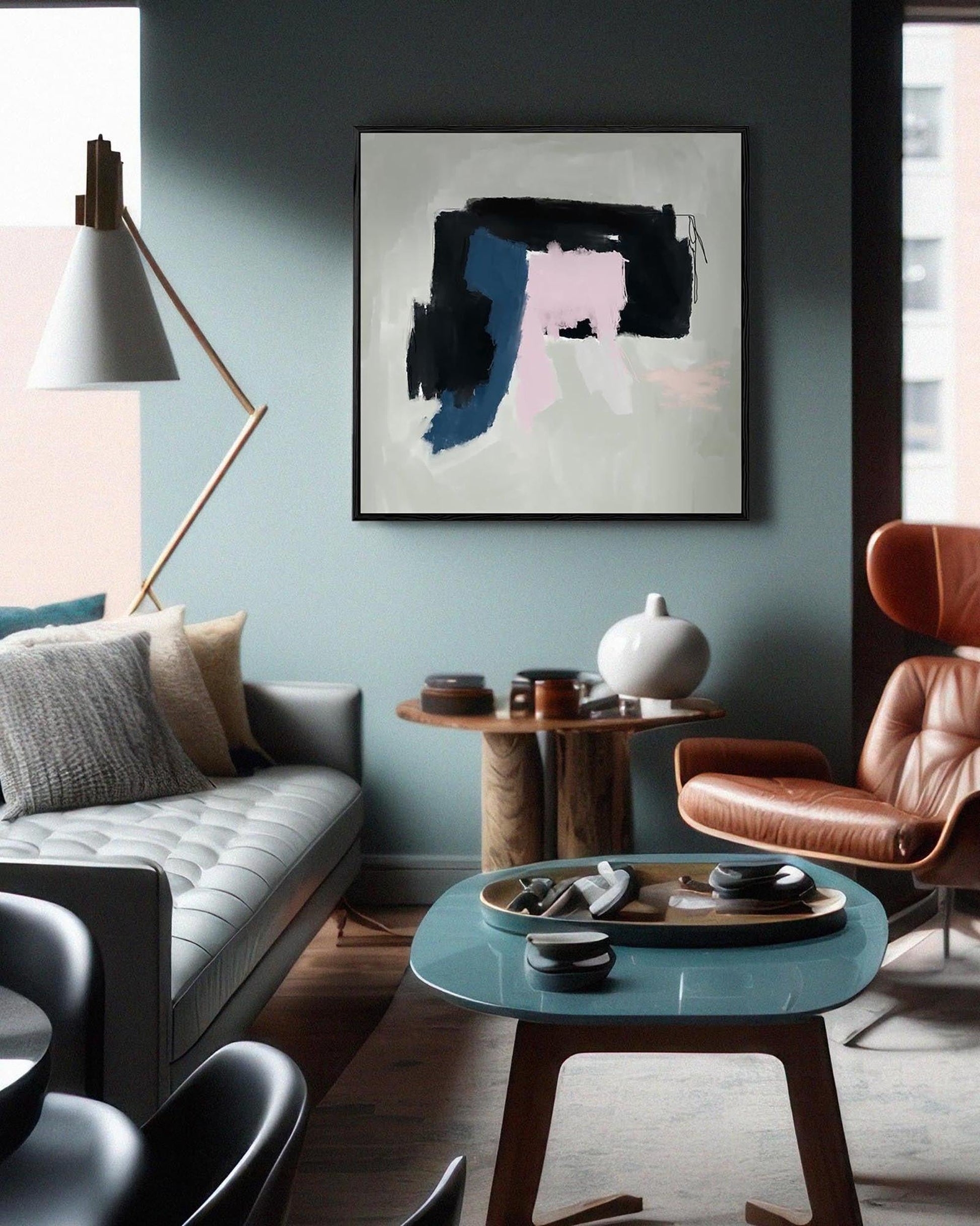 Modern living room with a gray sofa, brown leather chair, and abstract art on the wall.