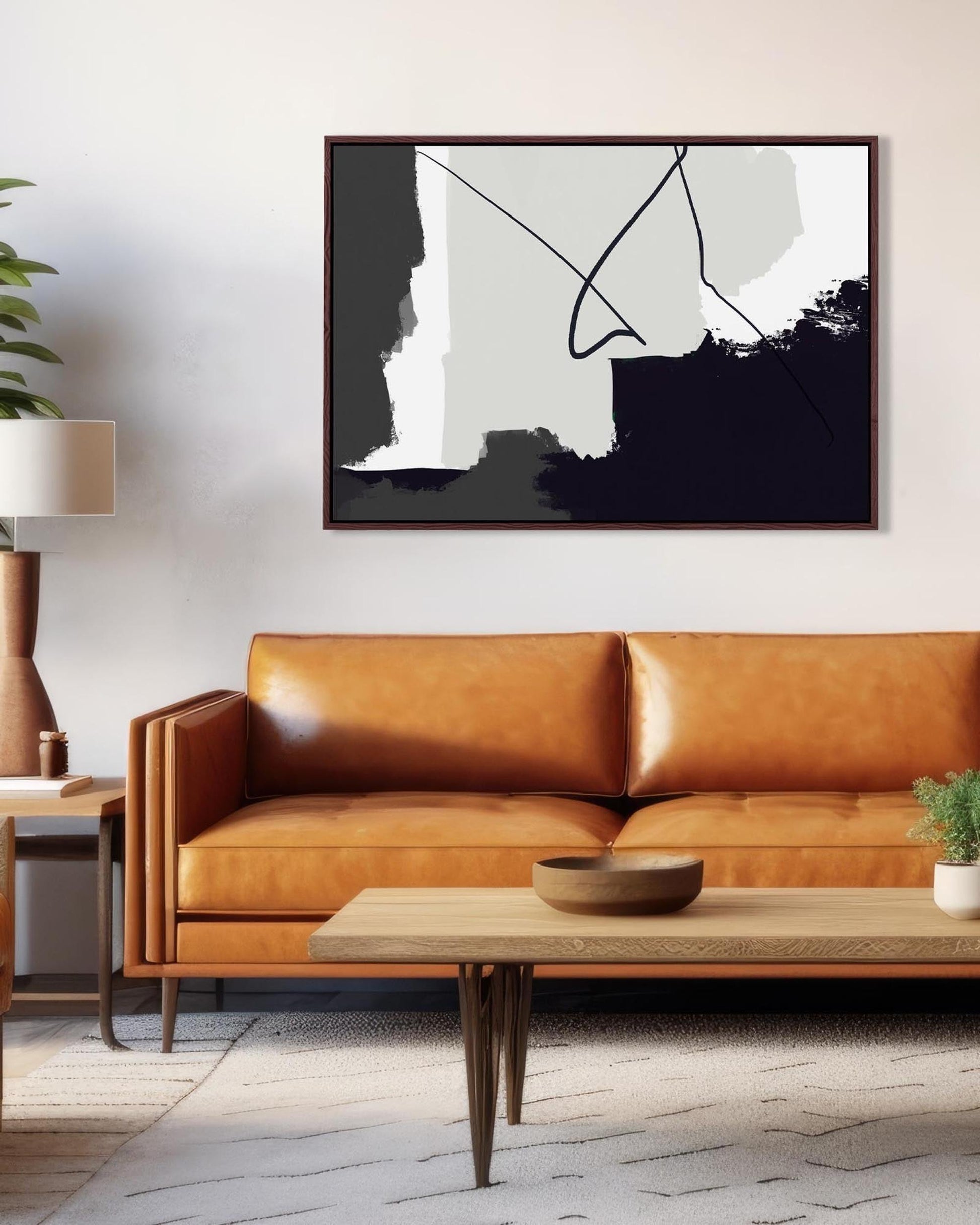 Modern living room with a brown leather sofa, abstract art on the wall, and a wooden coffee table.