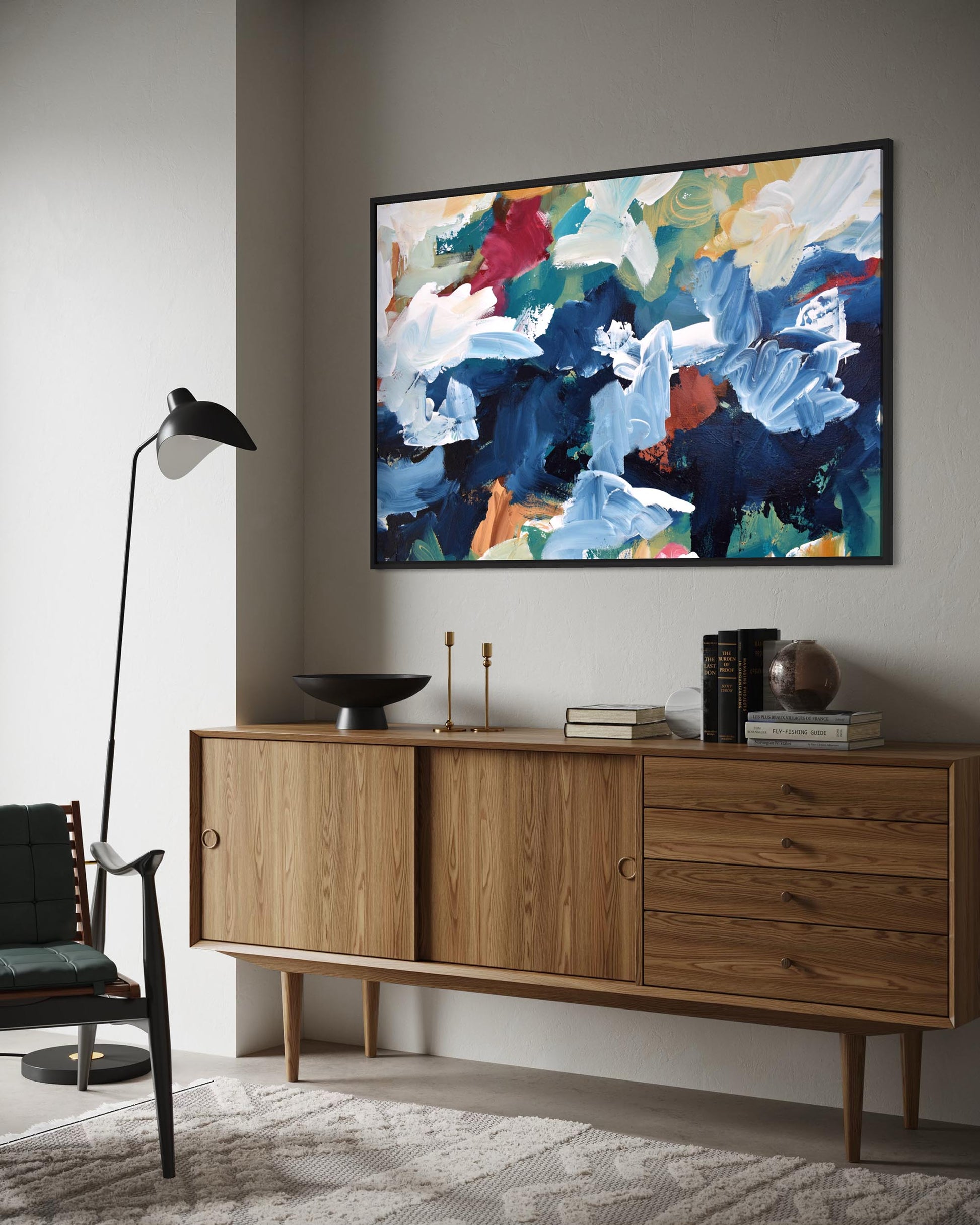 Wooden sideboard with decorative items against a wall with a colorful abstract painting.