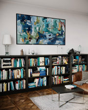 Living room with bookshelves, a painting, and a sofa.