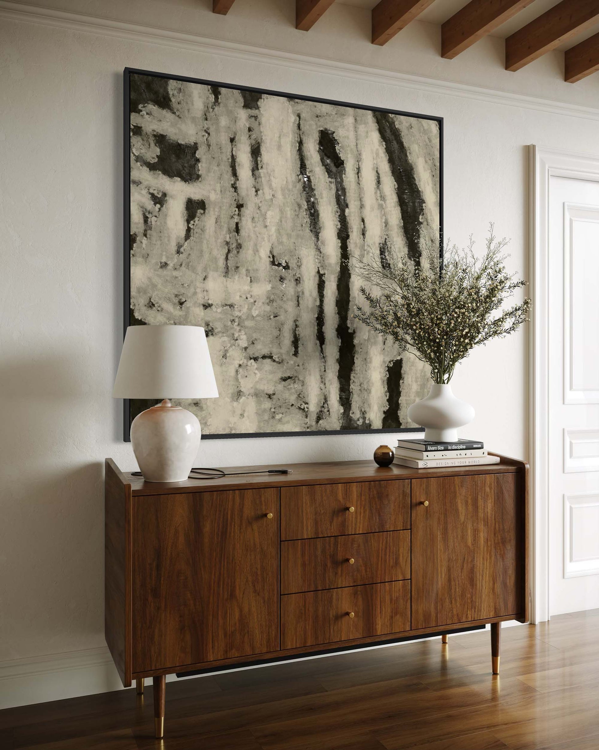 Wooden sideboard with a lamp and decorative items against a wall with abstract art.
