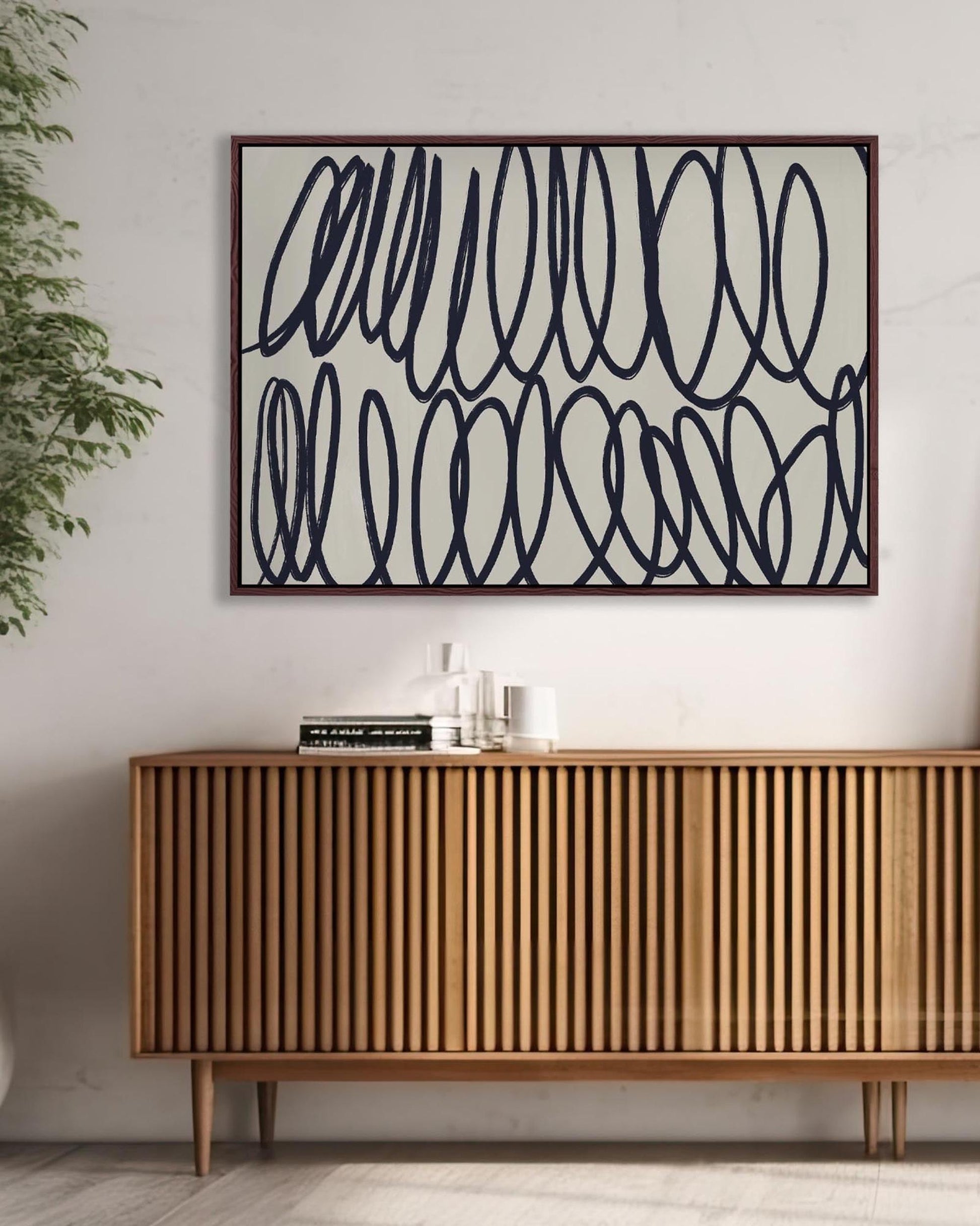 Abstract wall art above a wooden sideboard in a room with a plant.