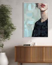 Framed abstract art on a wall above a wooden cabinet with a plant to the left.