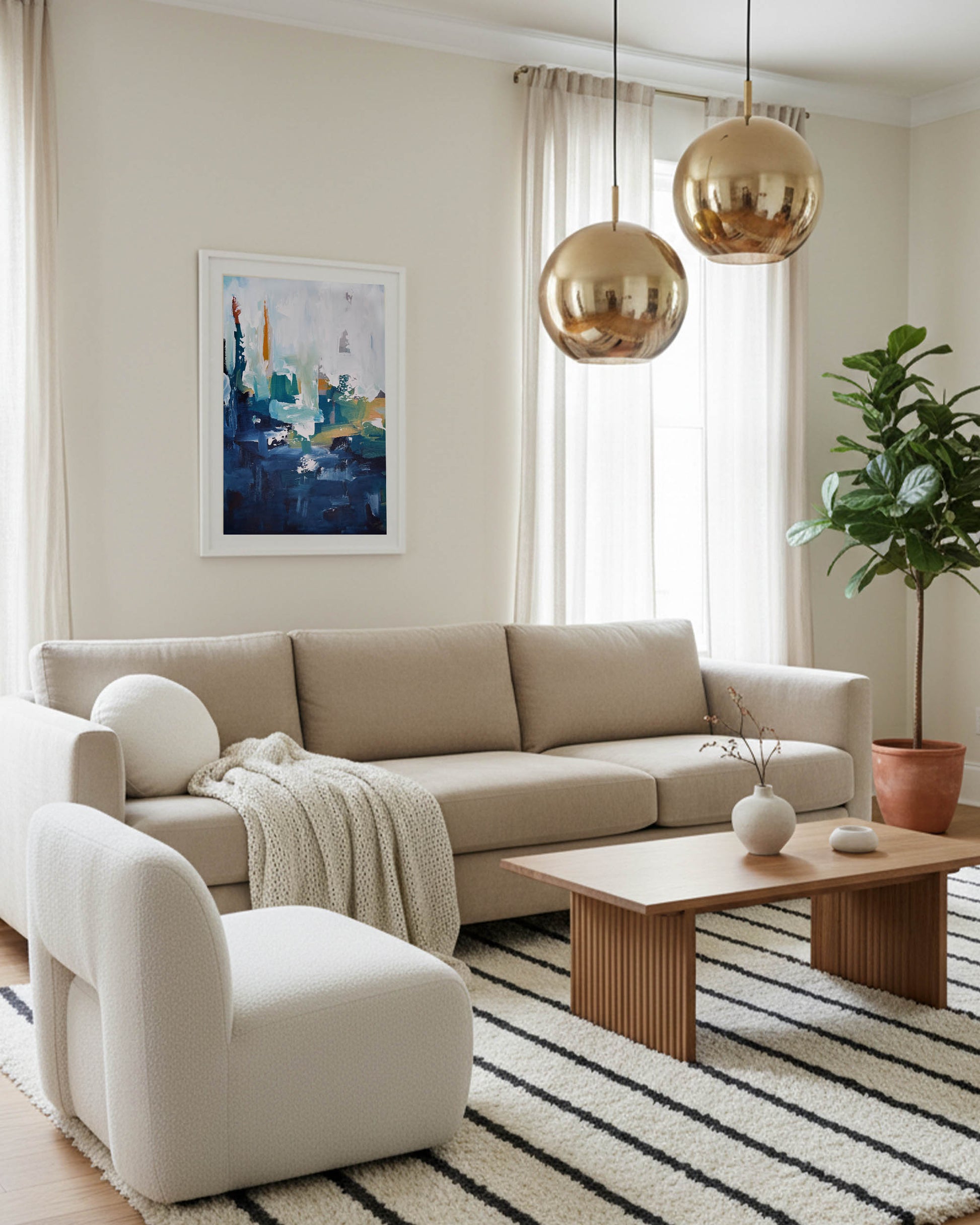 Large sandy beige coloured sofa with modern abstract navy and white blue seascape painting framed on wall, with scandinavian cream and black area rug
