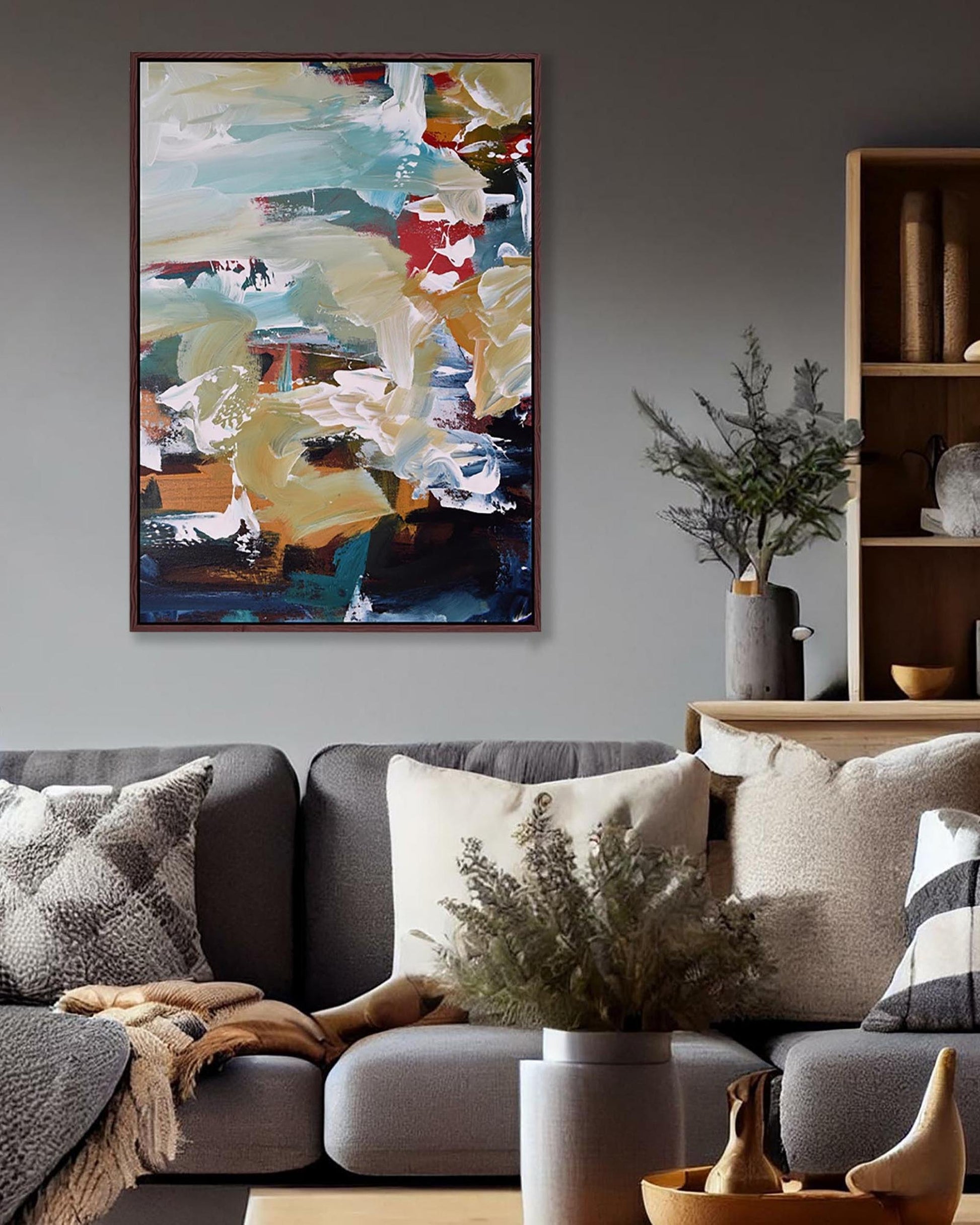 Living room with a gray sofa, decorative pillows, and a colorful abstract painting on the wall.