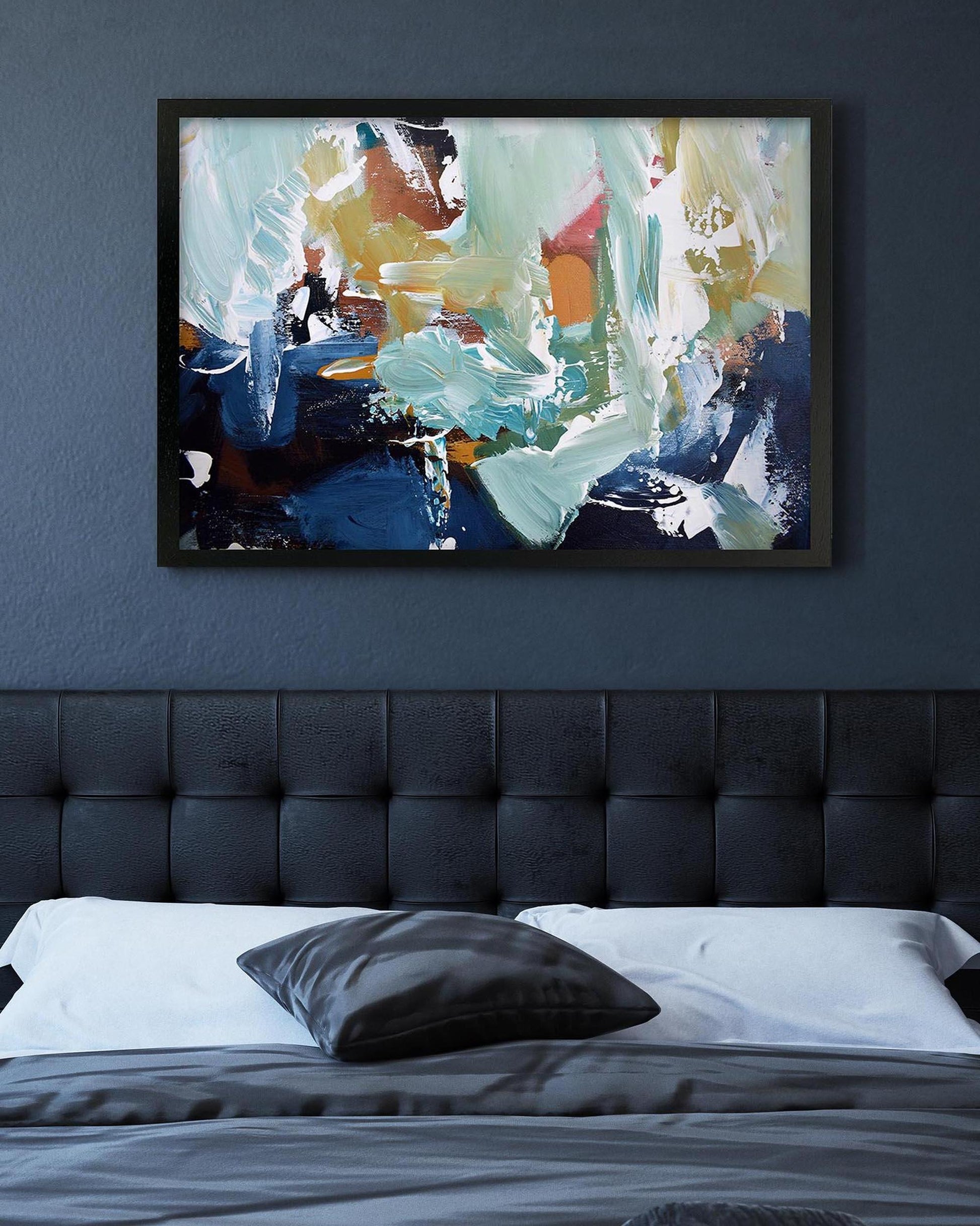 Abstract painting on a wall above a bed with a tufted headboard.