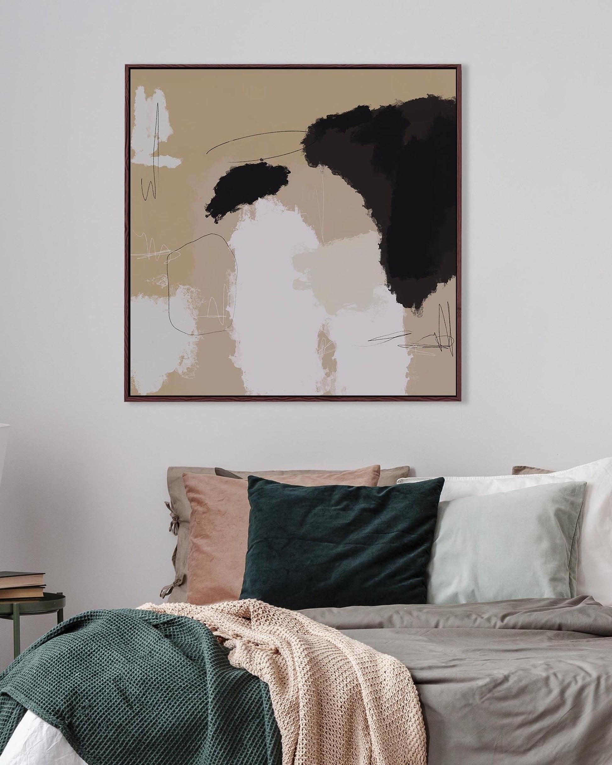 Abstract art piece on a wall above a bed with pillows and blankets.