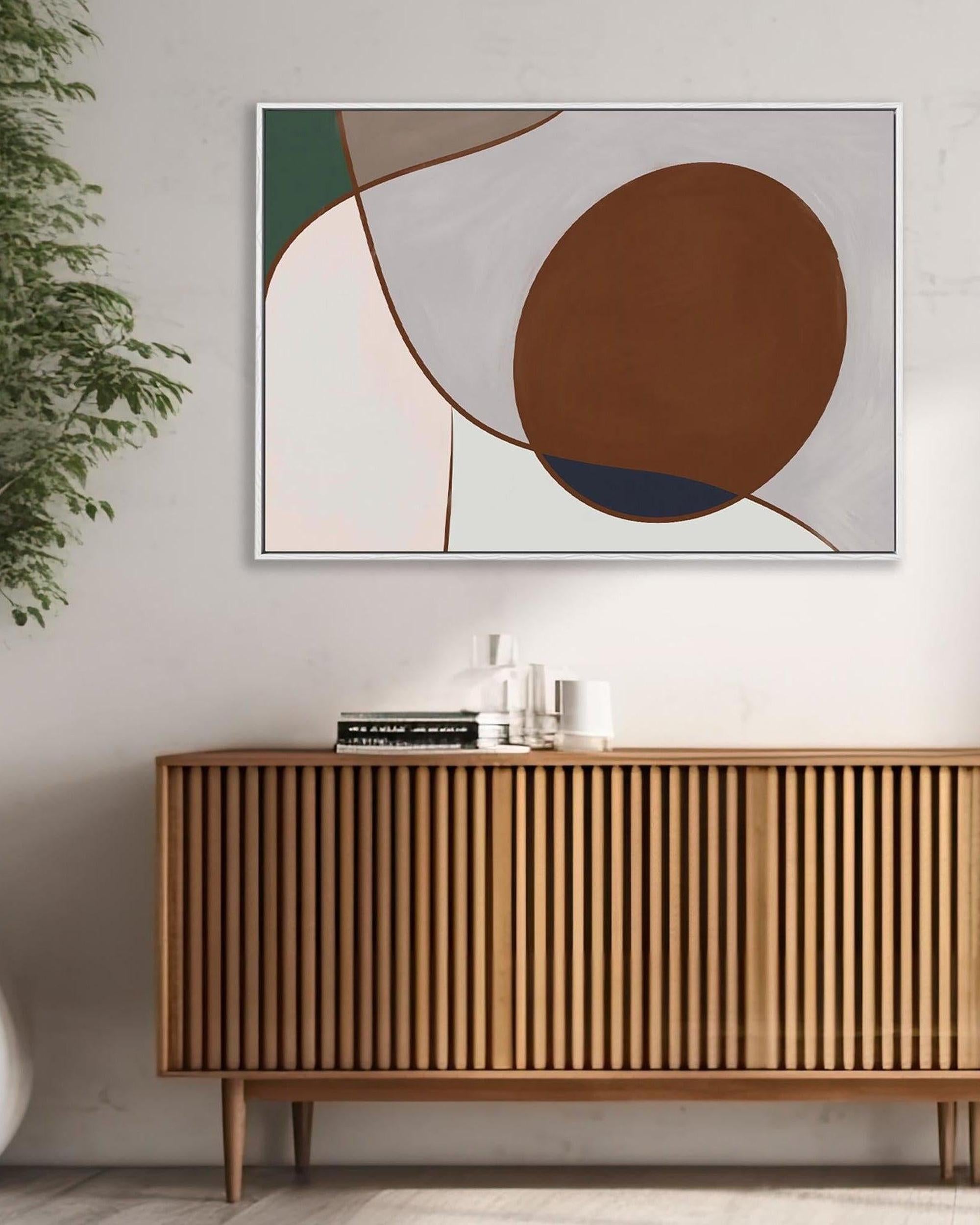 A framed canvas abstract wall art hanging above a wooden cabinet with a plant to the side, displaying geometric shapes in brown and beige tones.