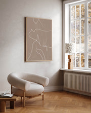 A modern abstract lines framed canvas art hanging on a wall over a white chair, with a window in the background.