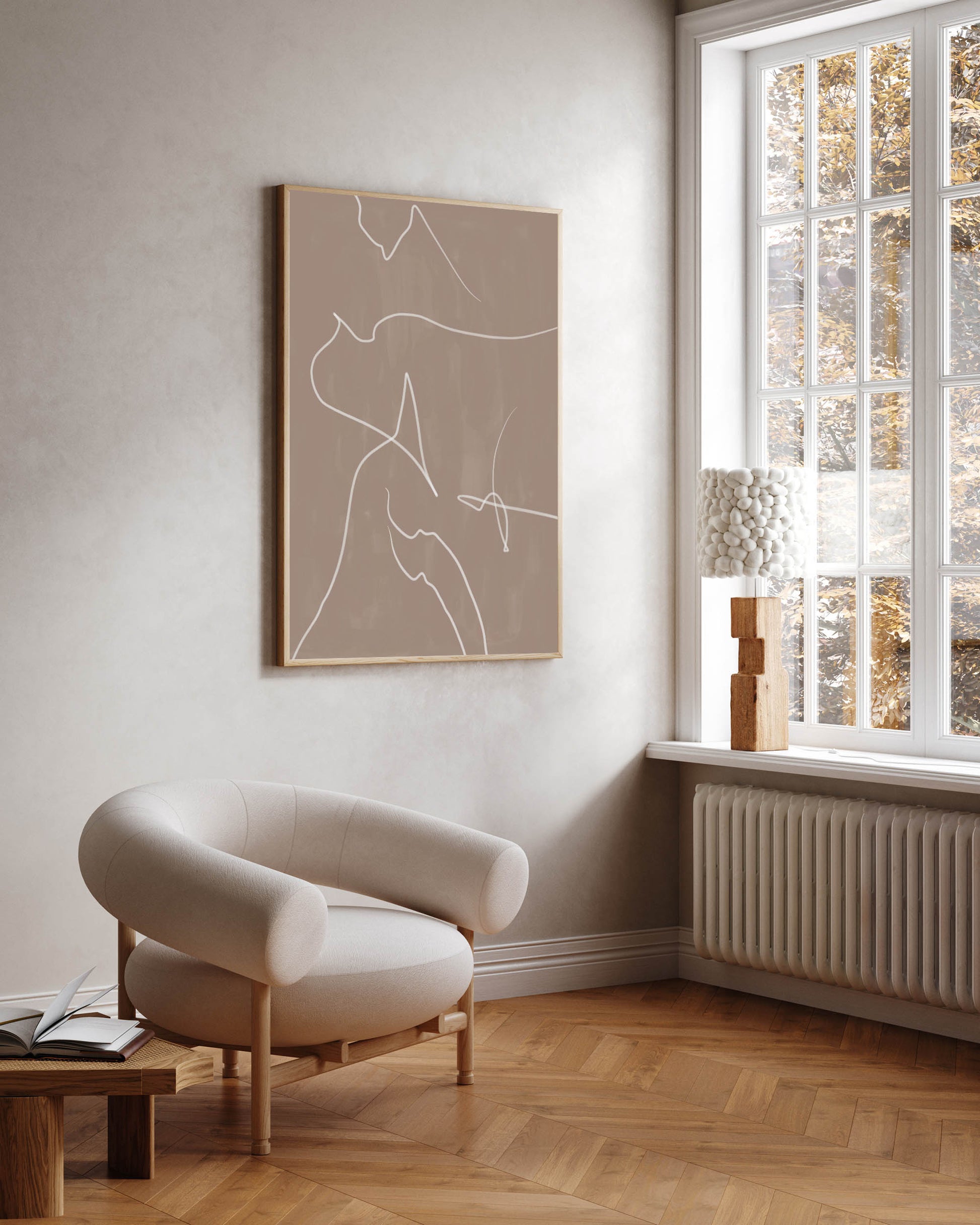 A modern abstract lines framed canvas art hanging on a wall over a white chair, with a window in the background.