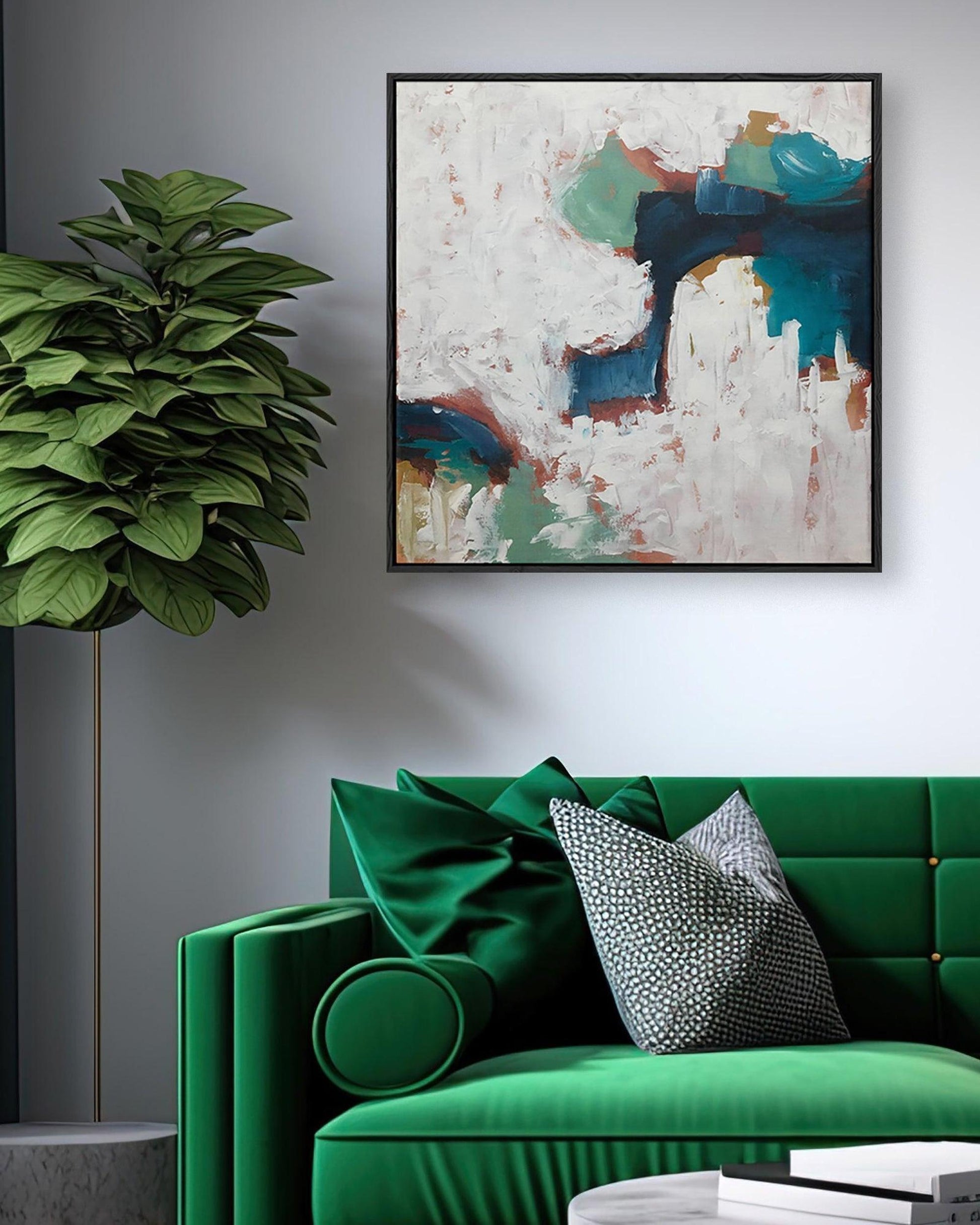 Green sofa with decorative pillows in a living room setting with abstract art on the wall.