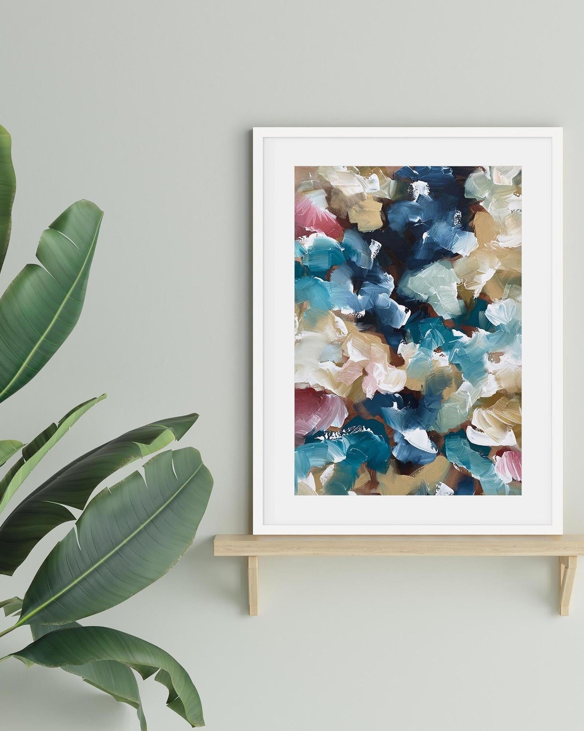 Framed abstract art print on a stand with green leaves in the foreground