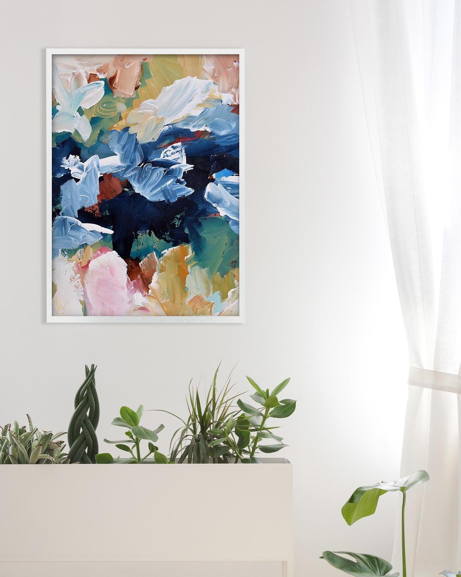 Colorful abstract painting on a white wall with plants below