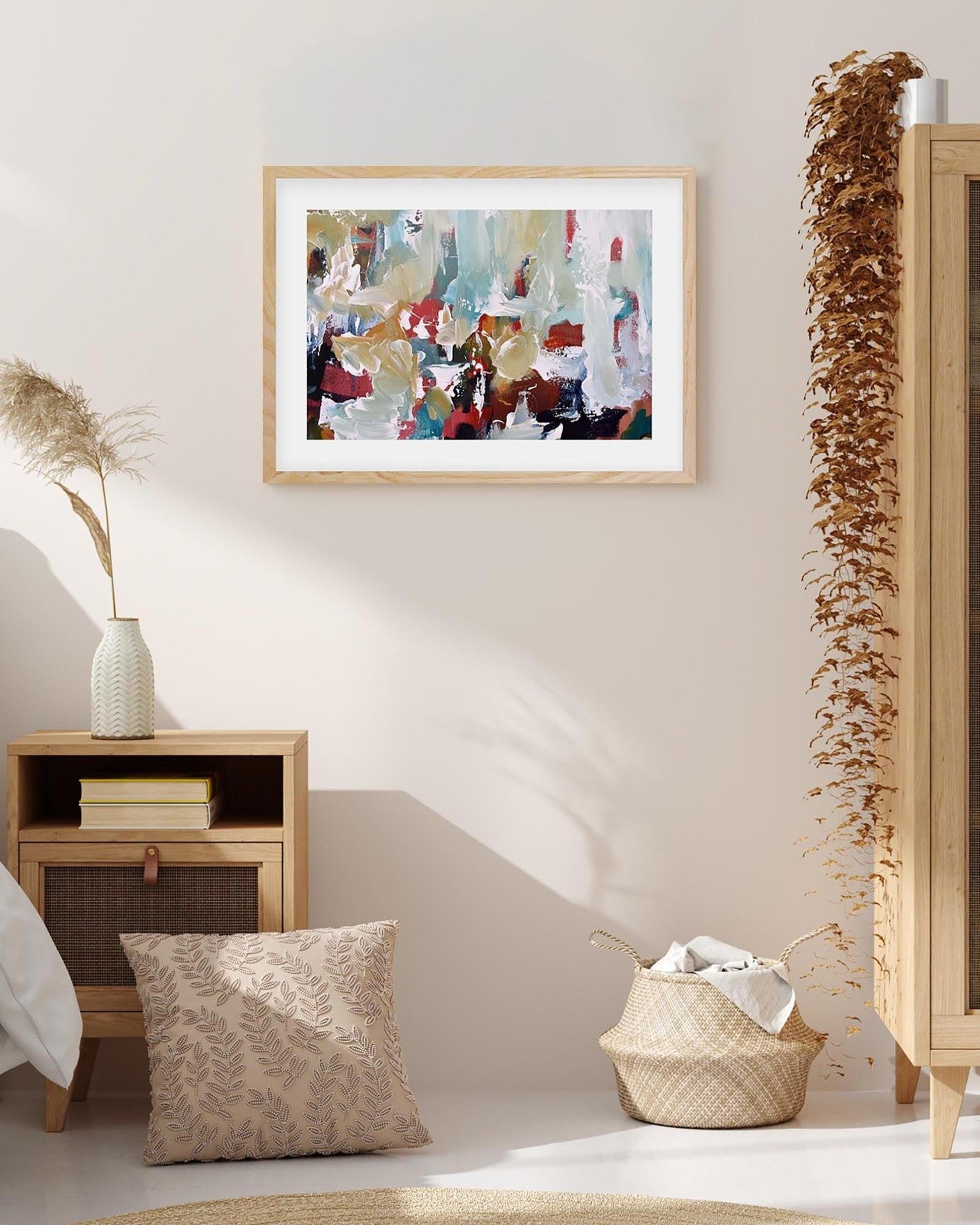 Framed abstract art piece on a wall with decorative elements like a vase, pillow, and basket.