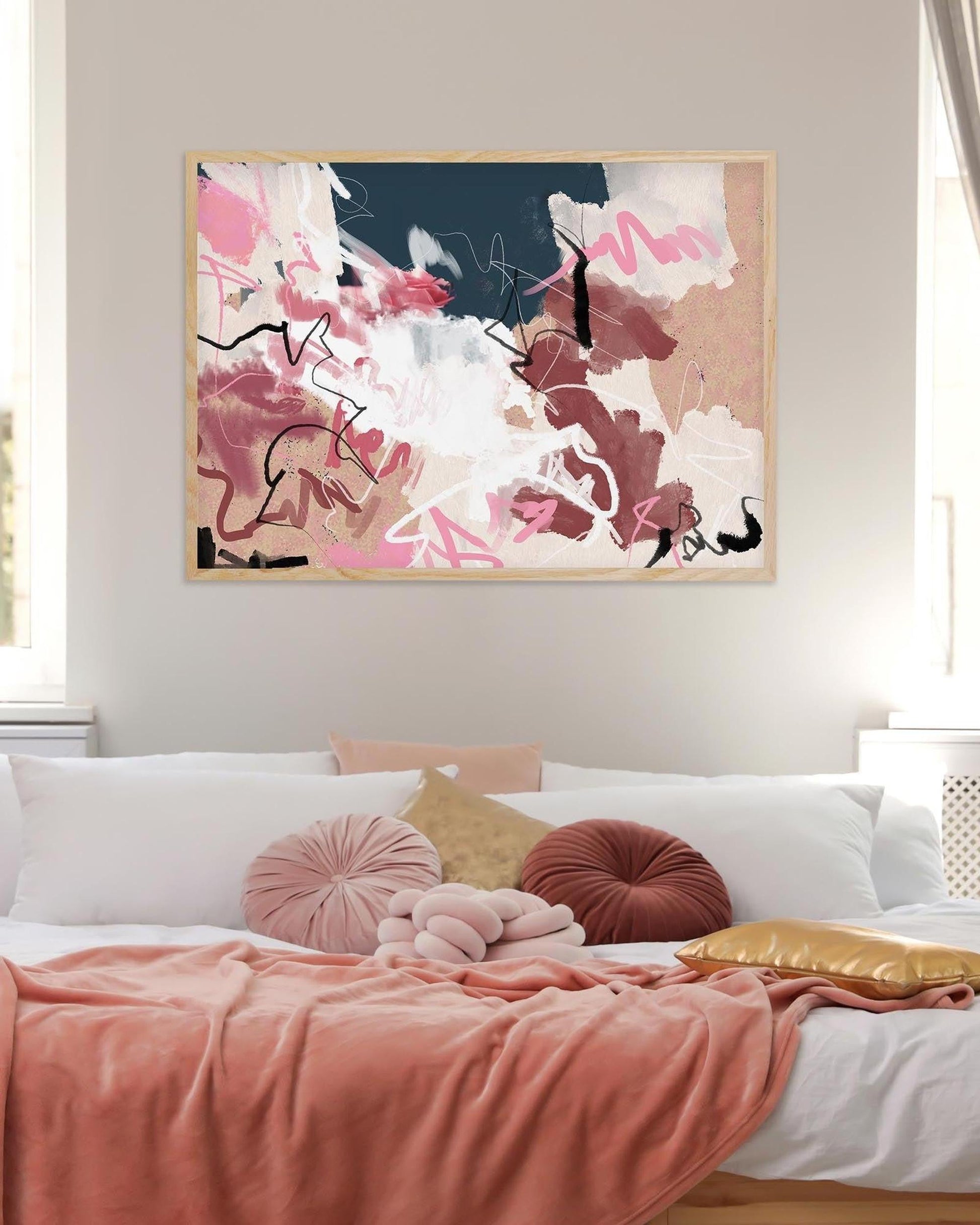 Abstract painting on a wall above a bed with colorful pillows.