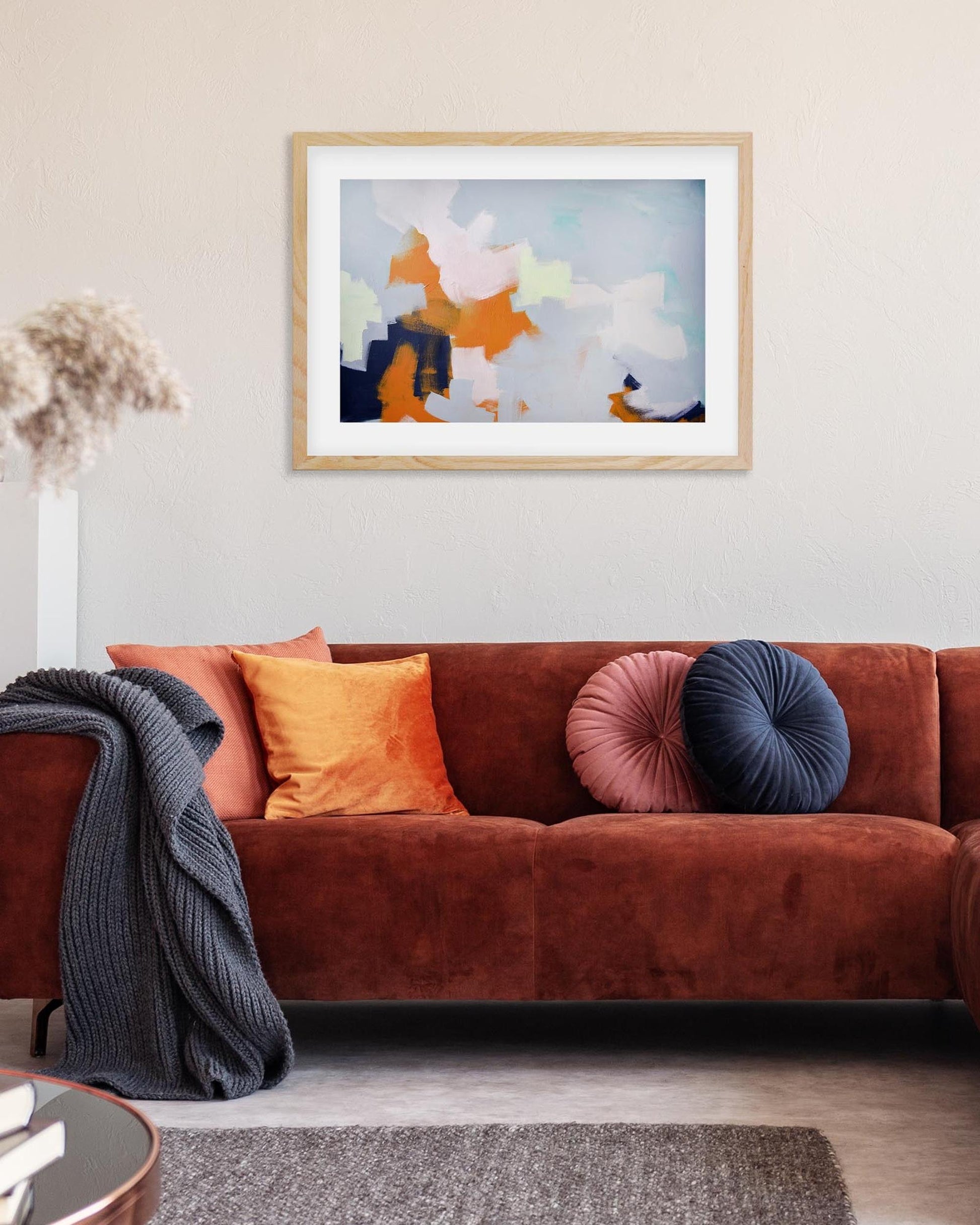 Living room with a brown sofa, colorful cushions, and a framed abstract painting on the wall.