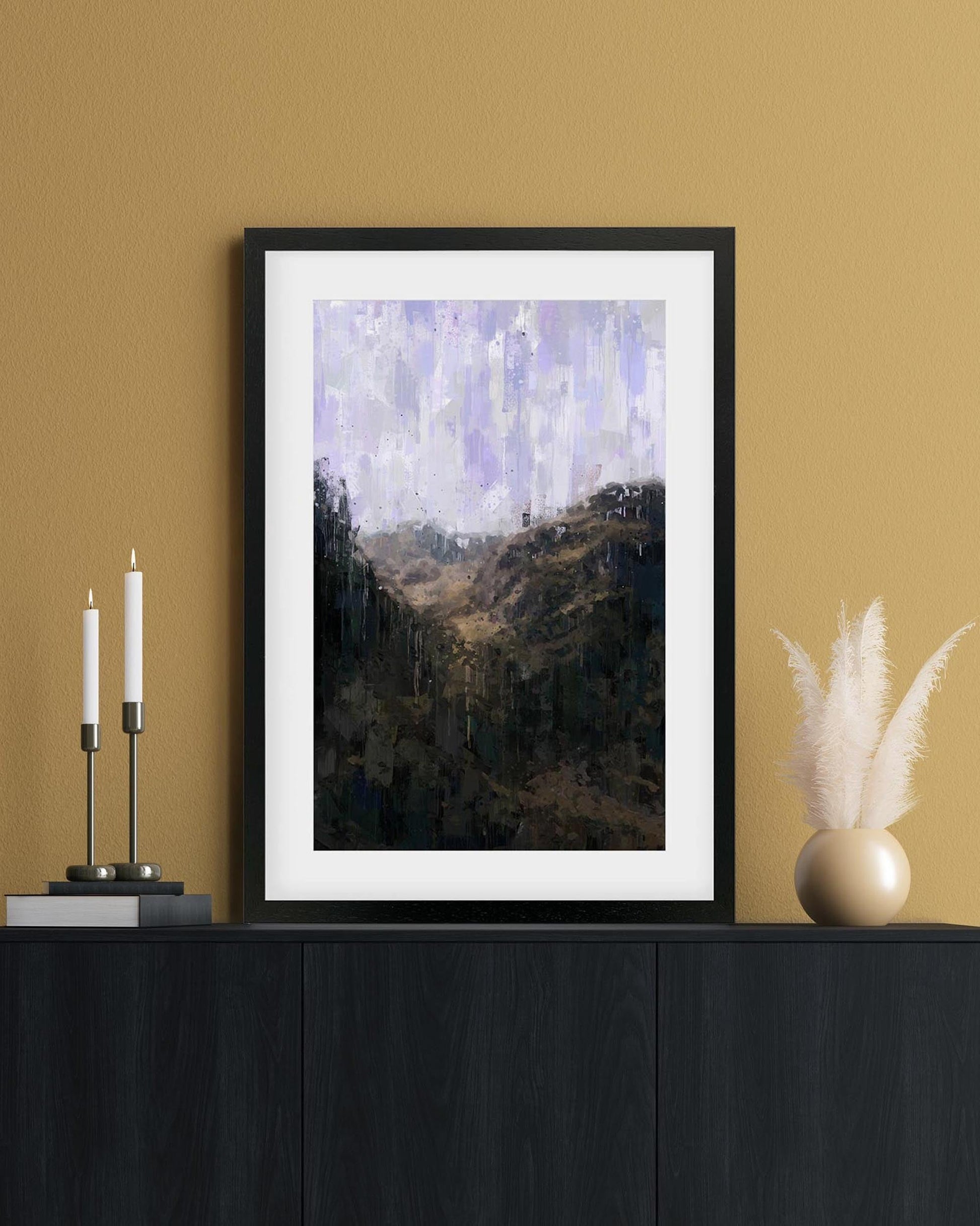 Framed artwork on a wall with candles and decorative items below