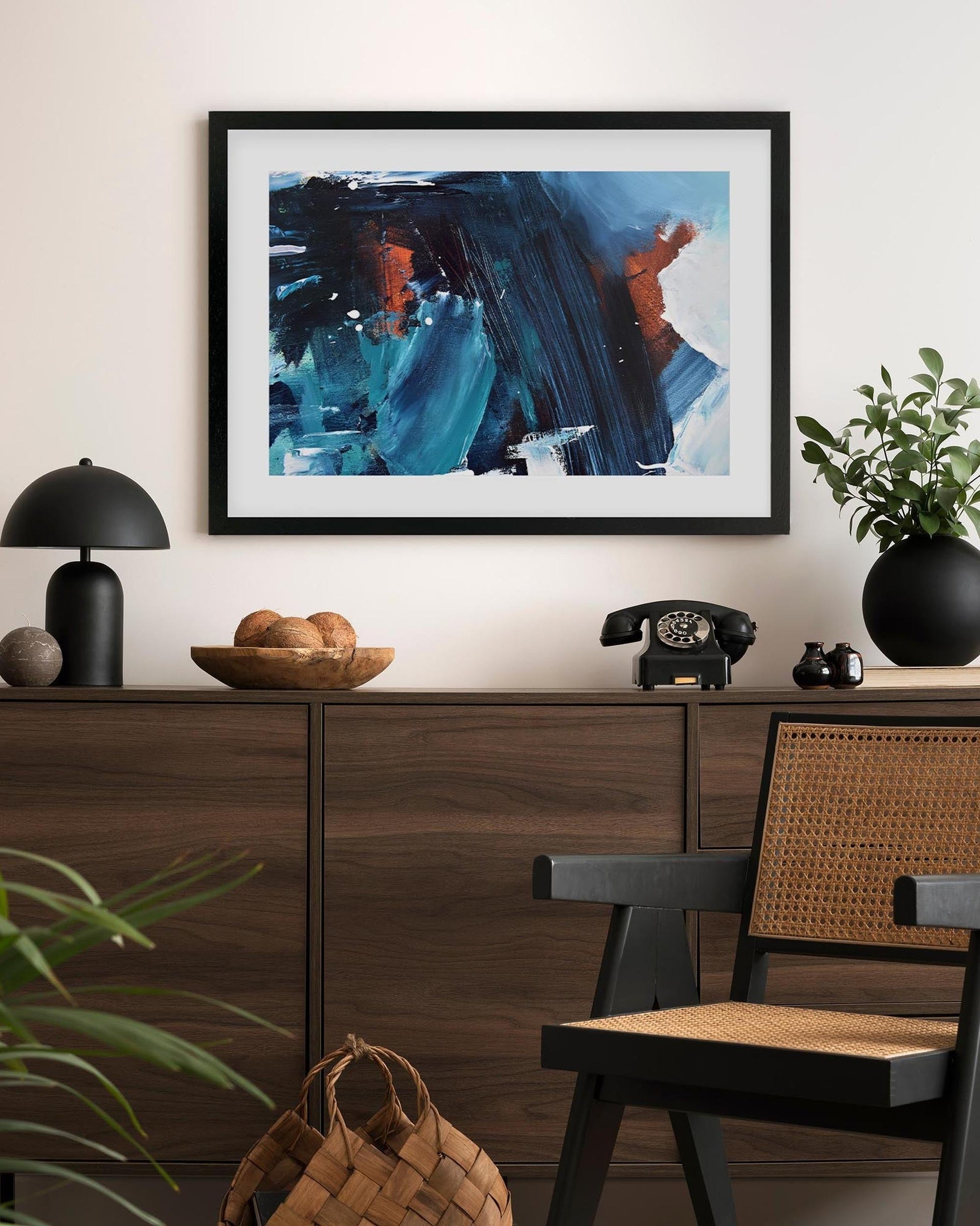 Framed abstract painting on a wall above a wooden console table with decorative items.