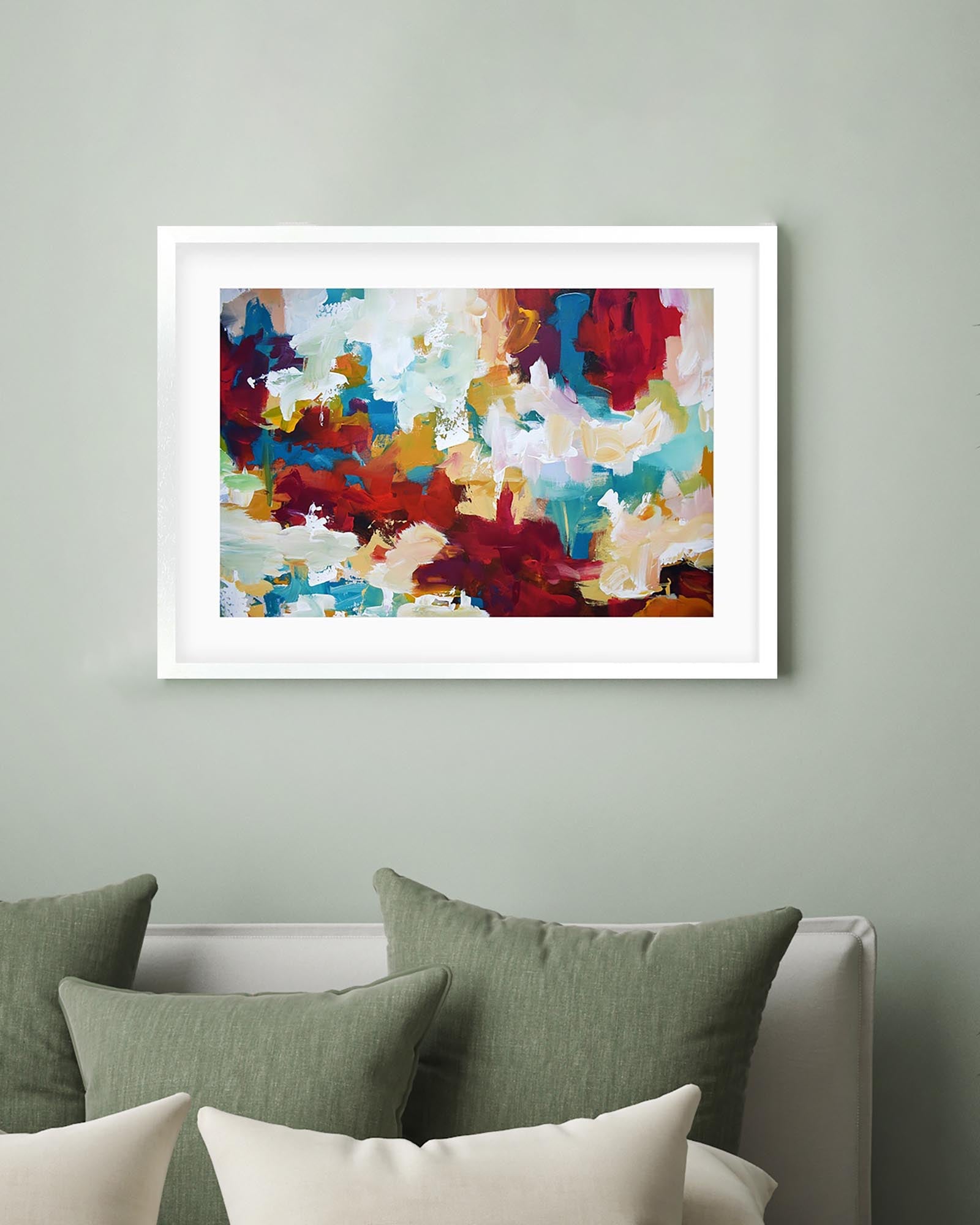 Framed abstract art on a wall above a bed with green and white pillows.