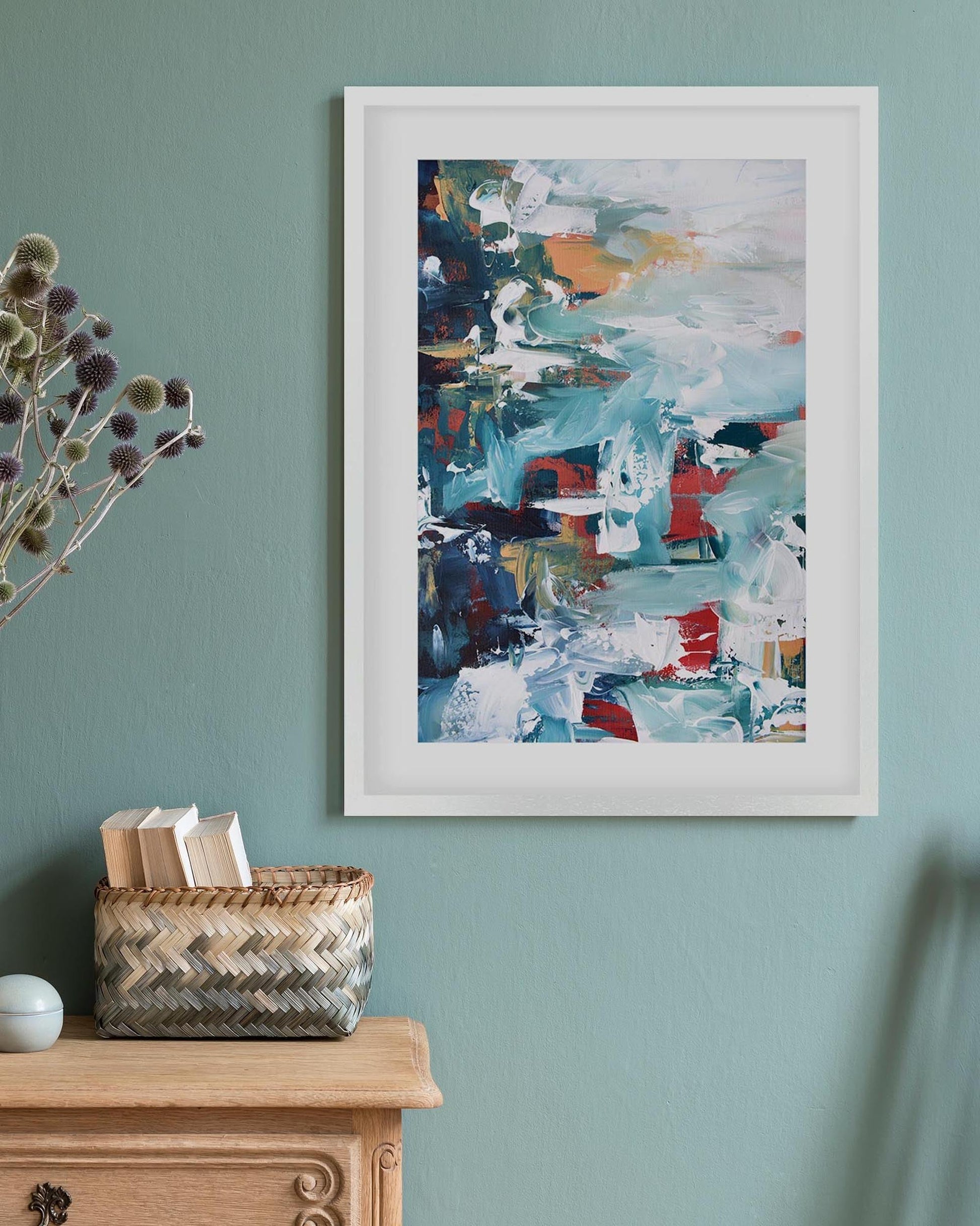 abstract artwork in a white frame on a teal green wall