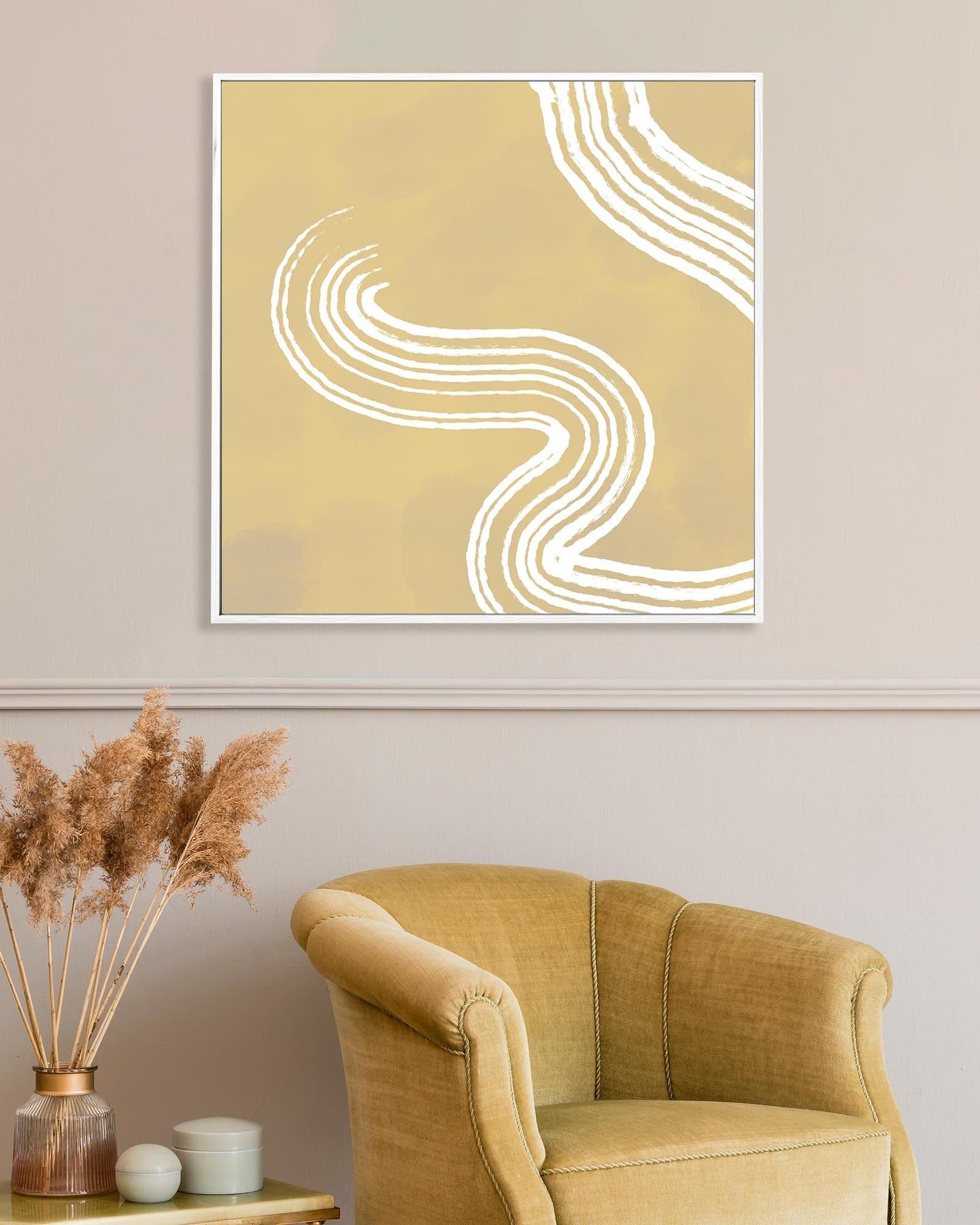 Abstract wall art with wavy lines on a beige wall above a mustard yellow armchair.