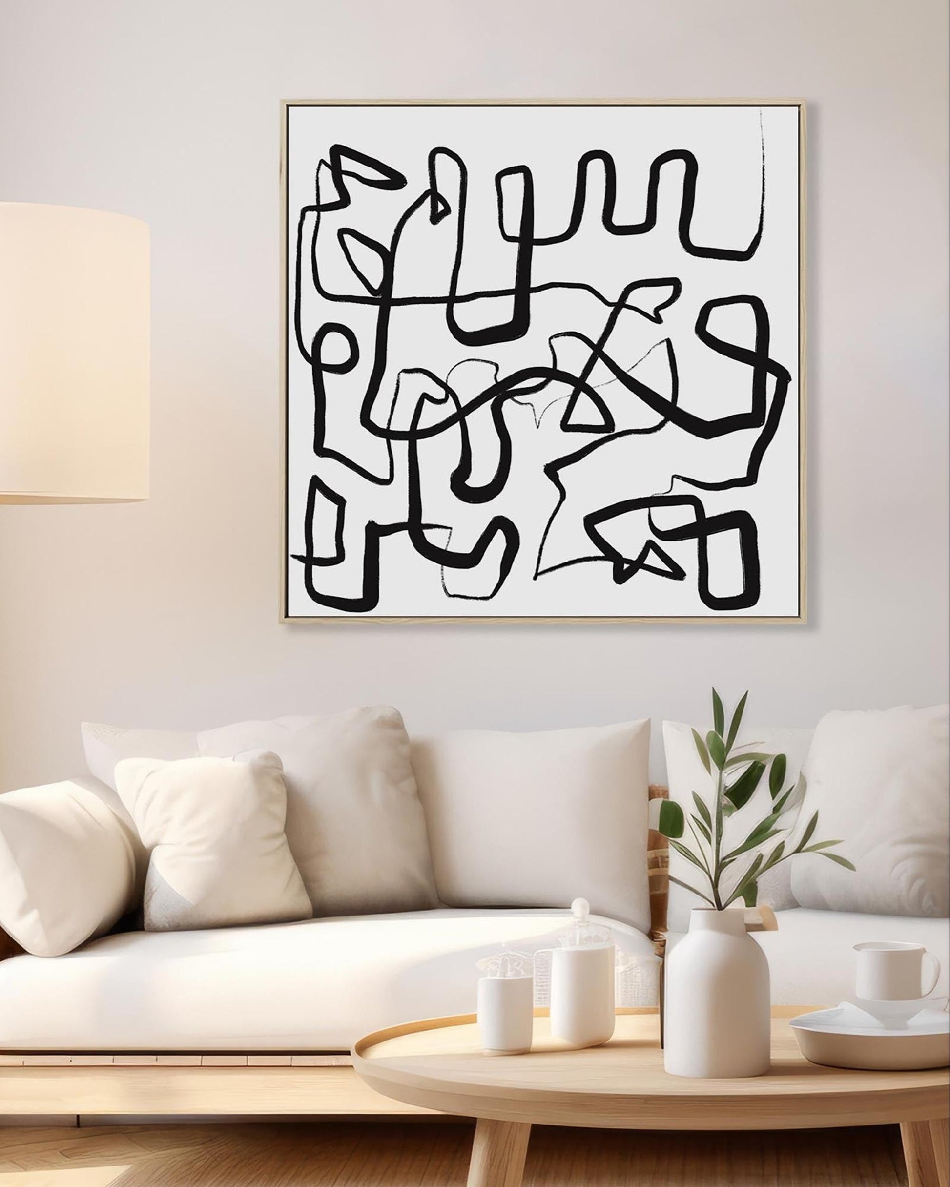 Abstract black line art on a white wall above a sofa in a living room.