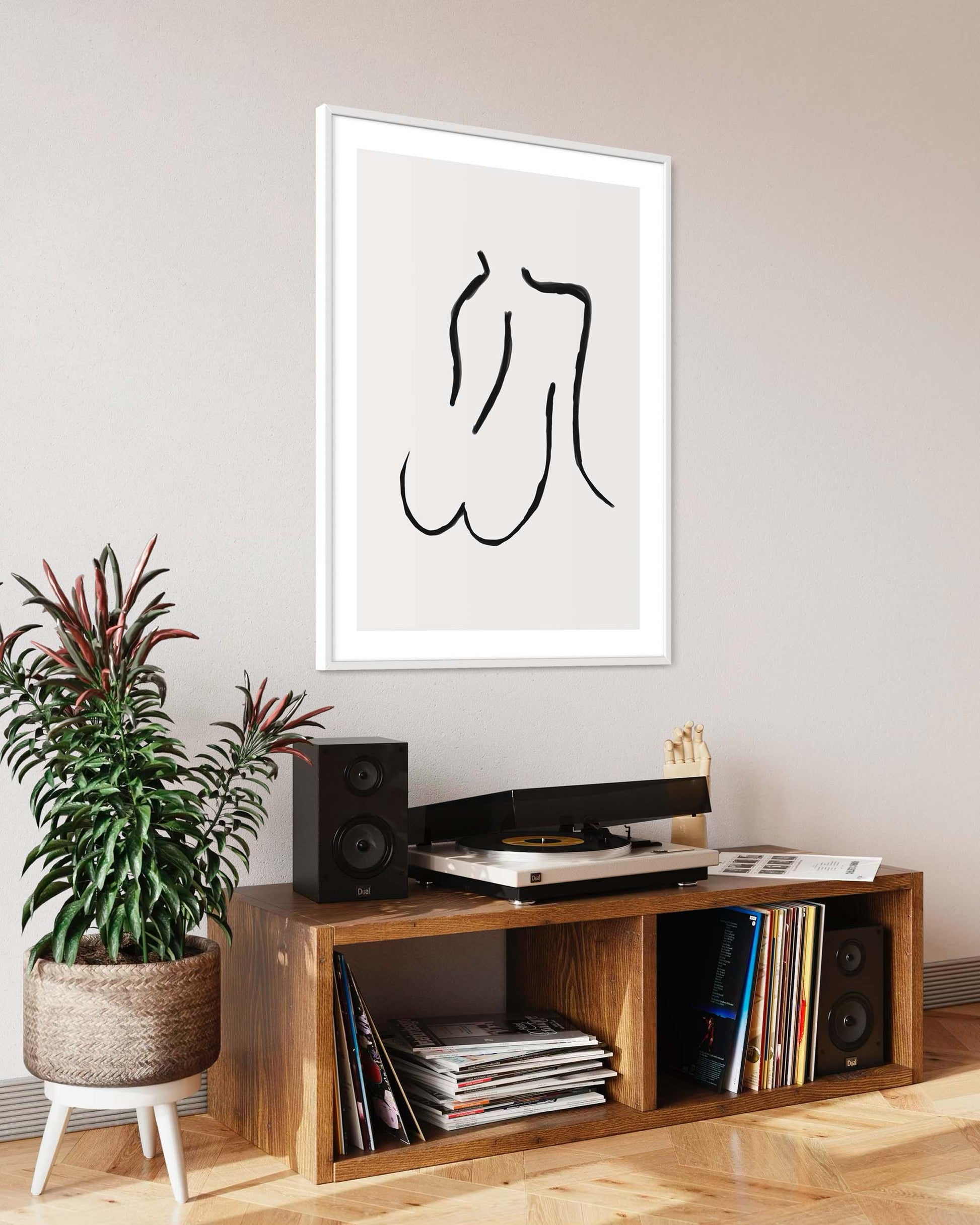 Framed abstract art above a wooden entertainment console with records and speakers.