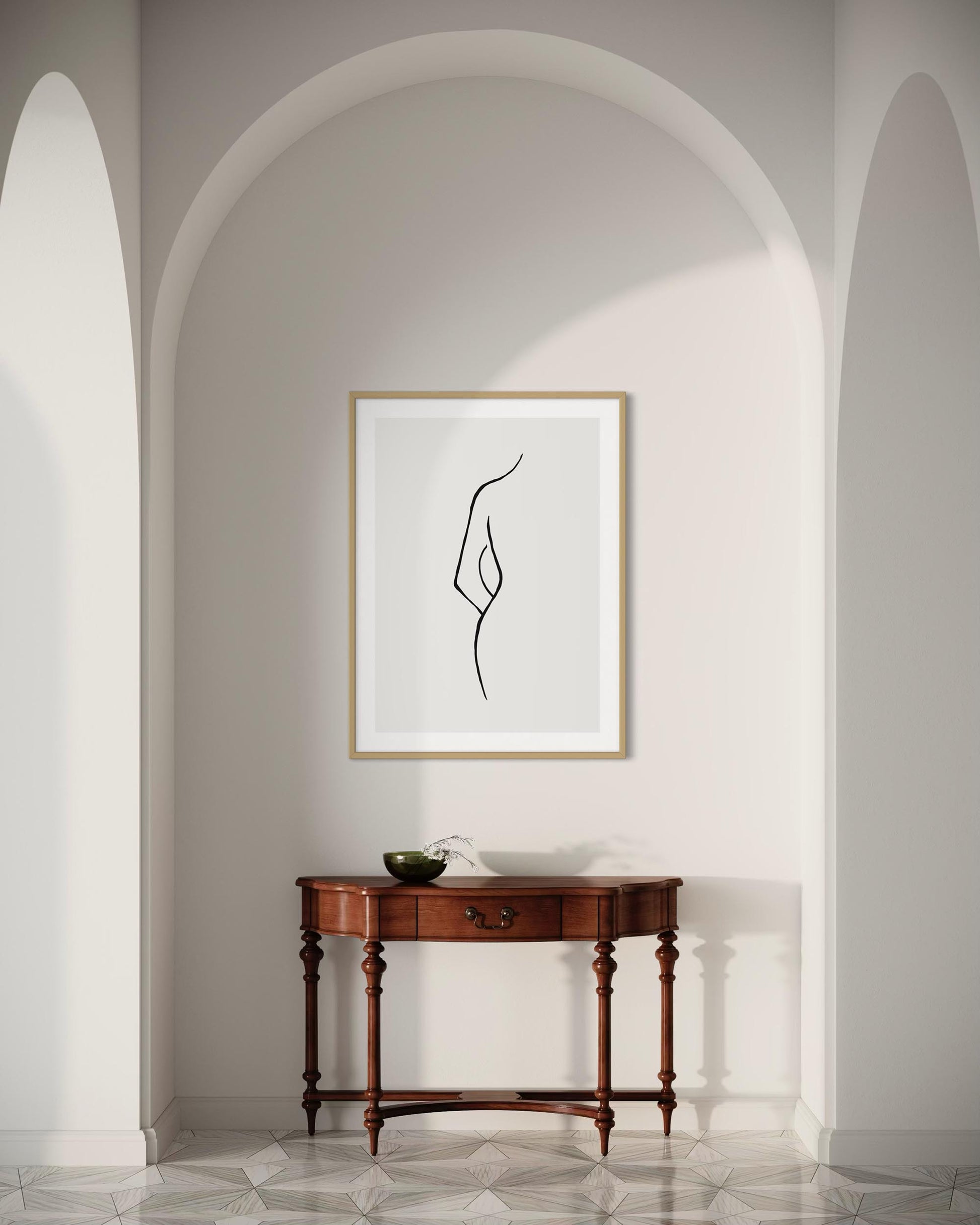 Framed abstract art on a wall above a wooden console table in a room with arched doorways.