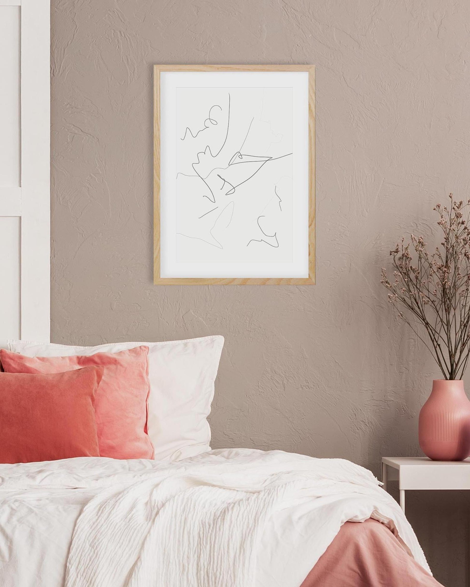 Framed abstract artwork on a wall above a bed with pink and white bedding.