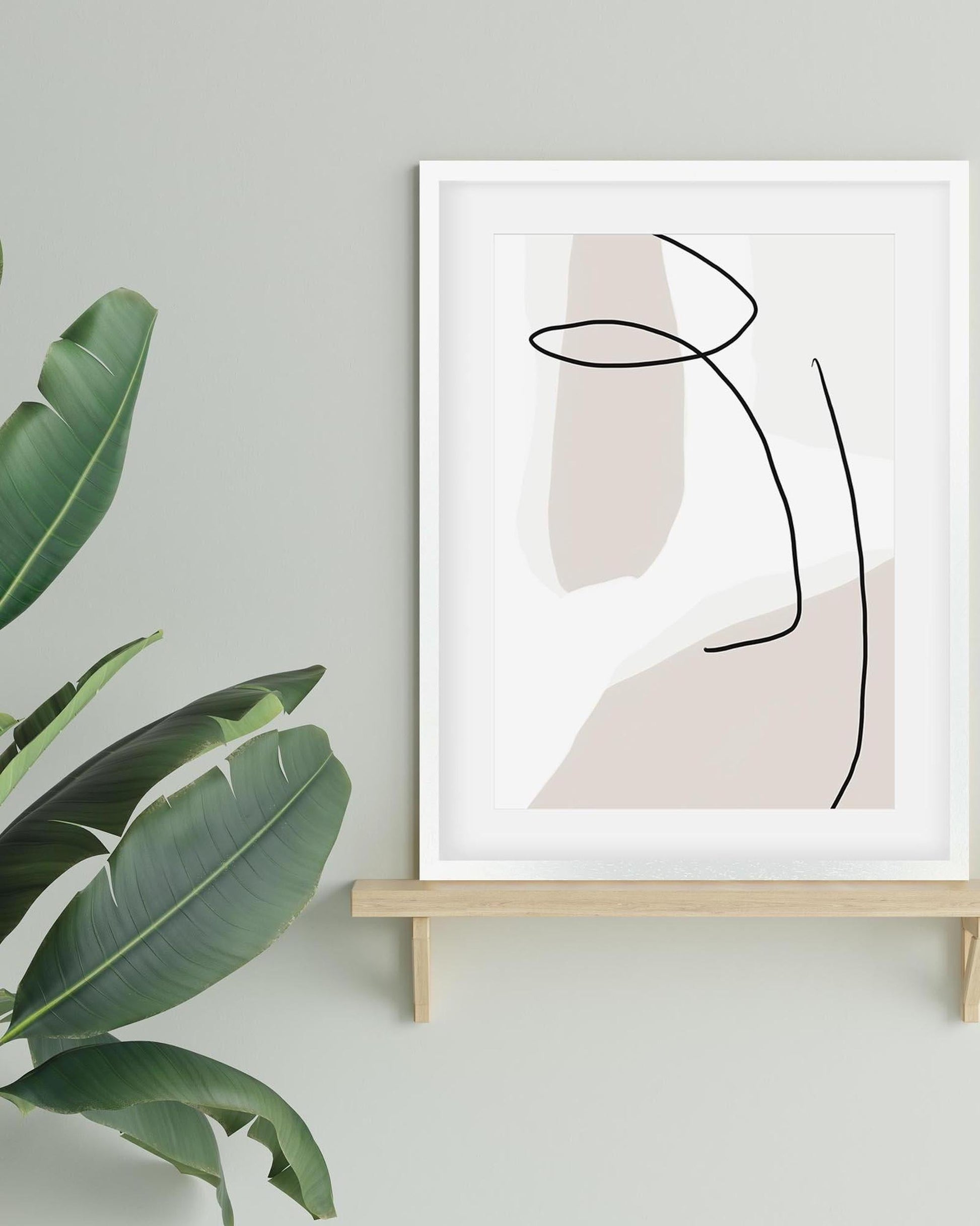 Abstract art print on a stand with a plant to the left against a light gray wall