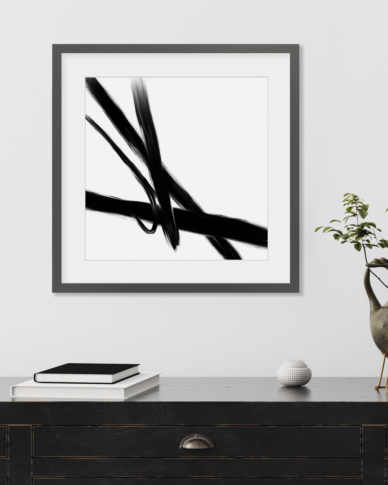 Framed black and white abstract art print on a wall above a wooden console table.
