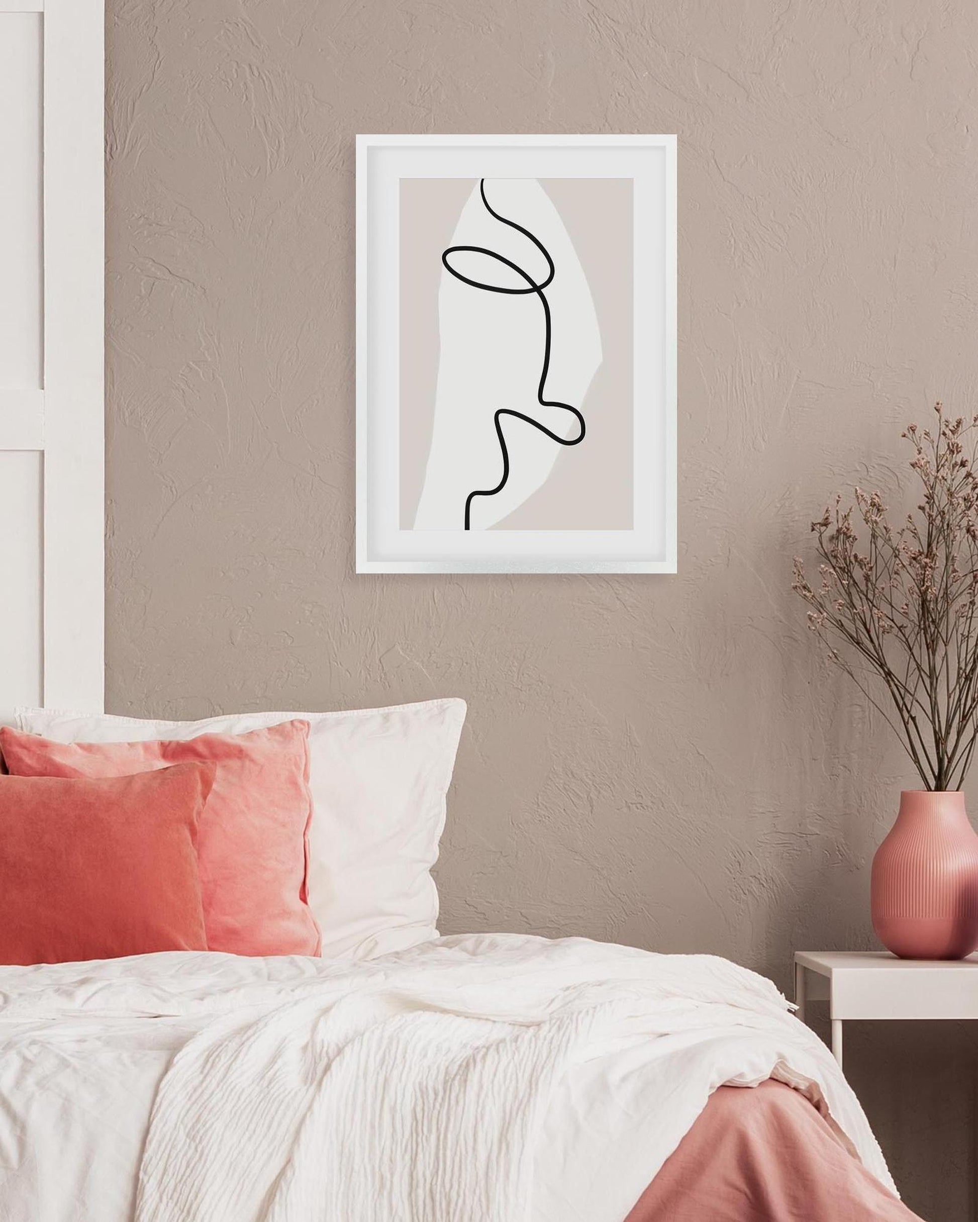 Framed abstract line art on a wall above a bed with pink and white bedding.