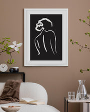 Framed black and white abstract artwork on a wall with decor elements.