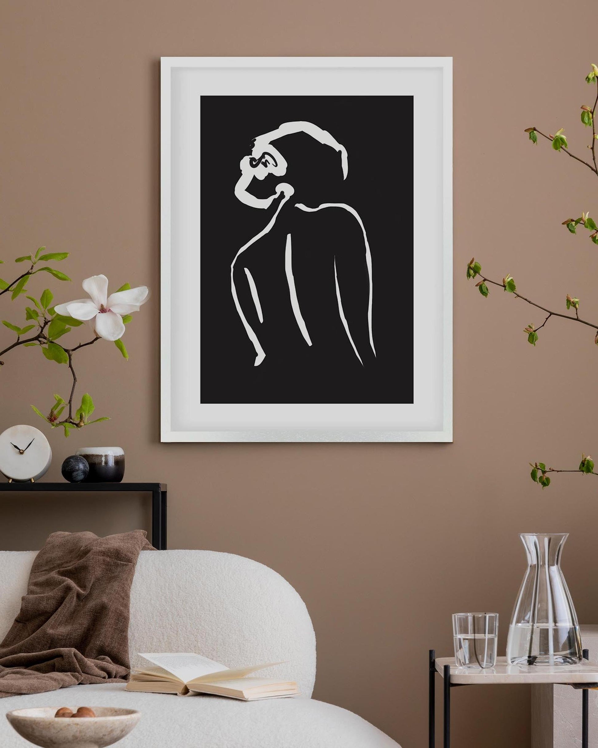 Framed black and white abstract artwork on a wall with decor elements.