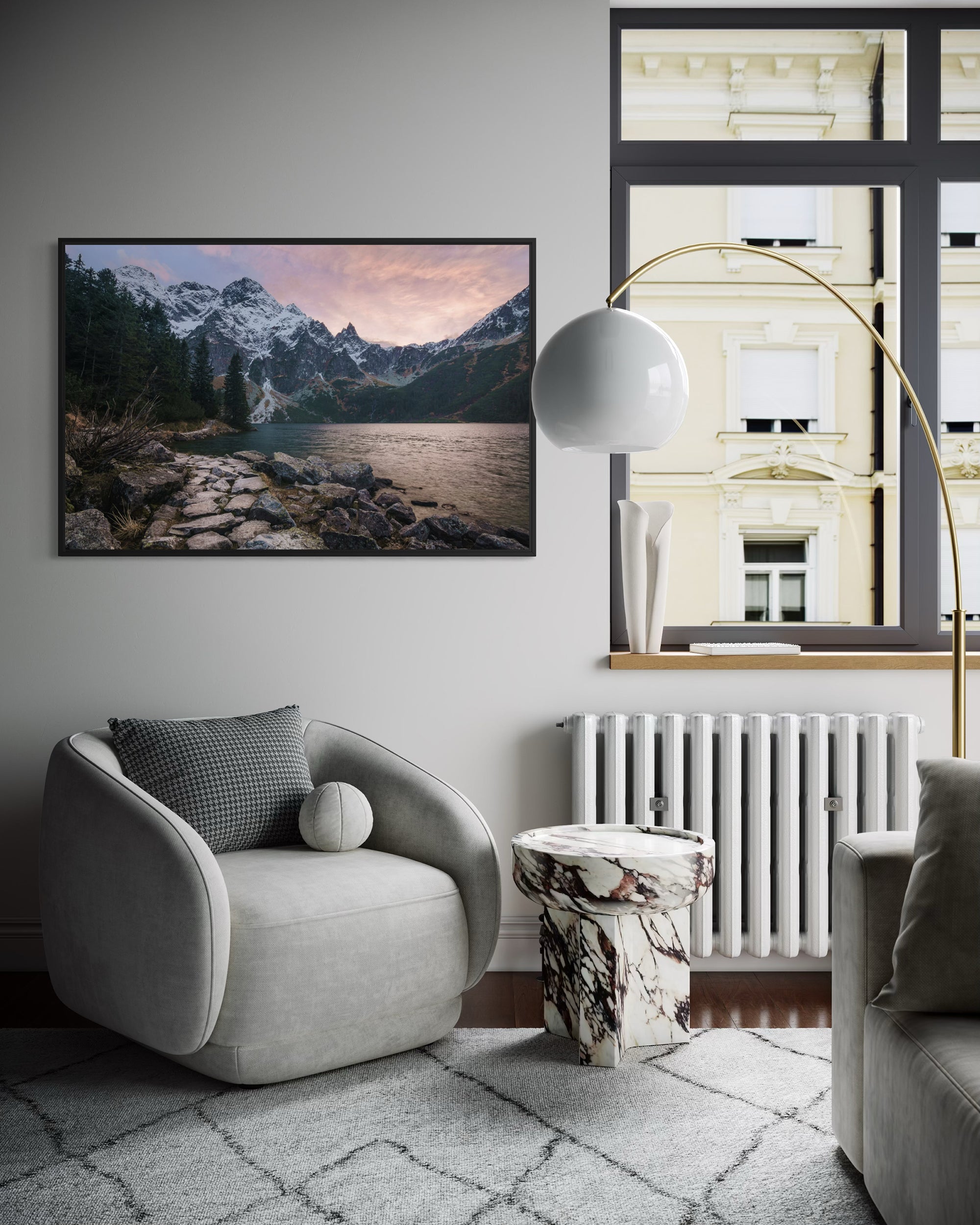 Modern living room with a gray armchair, marble side table, and mountain landscape artwork.