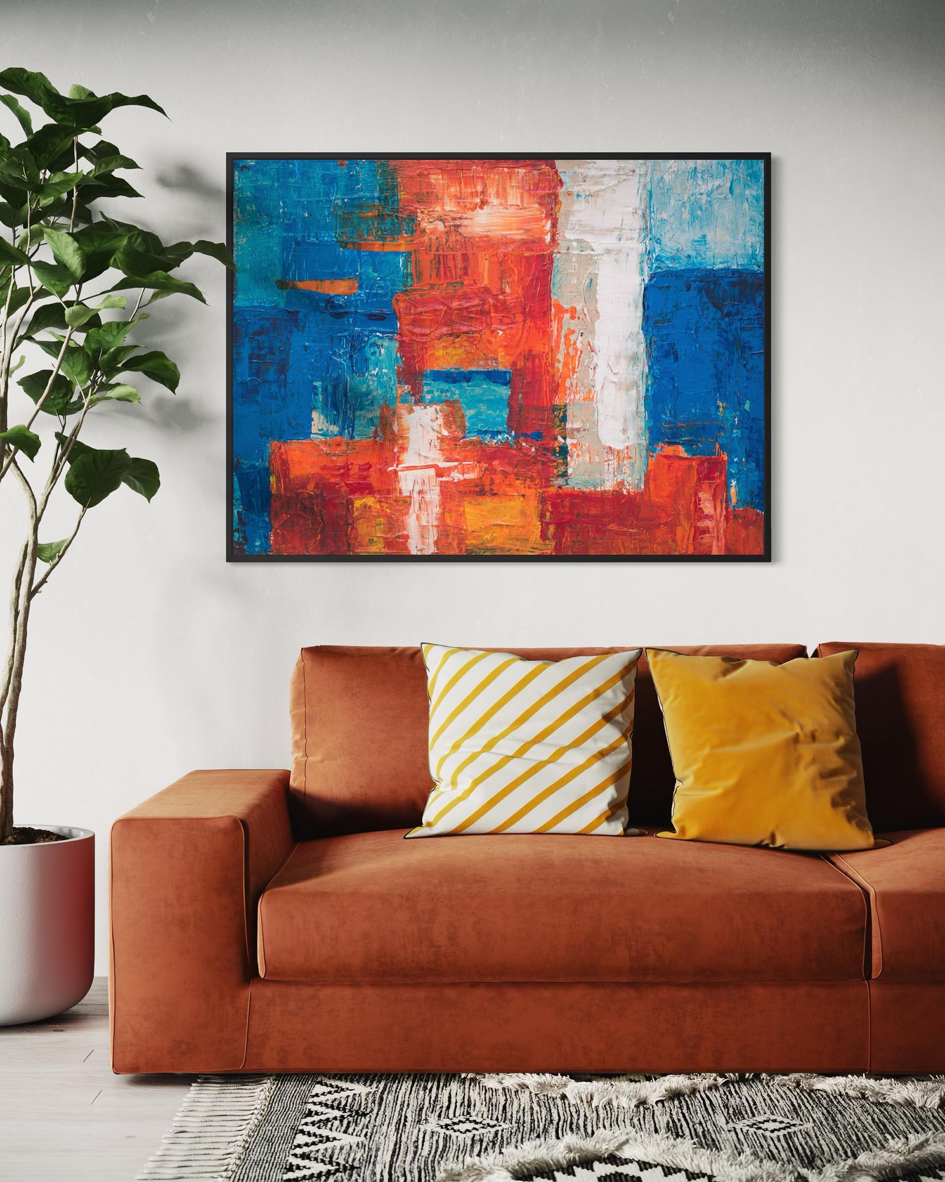 Abstract painting above a brown sofa with colorful cushions in a living room setting.