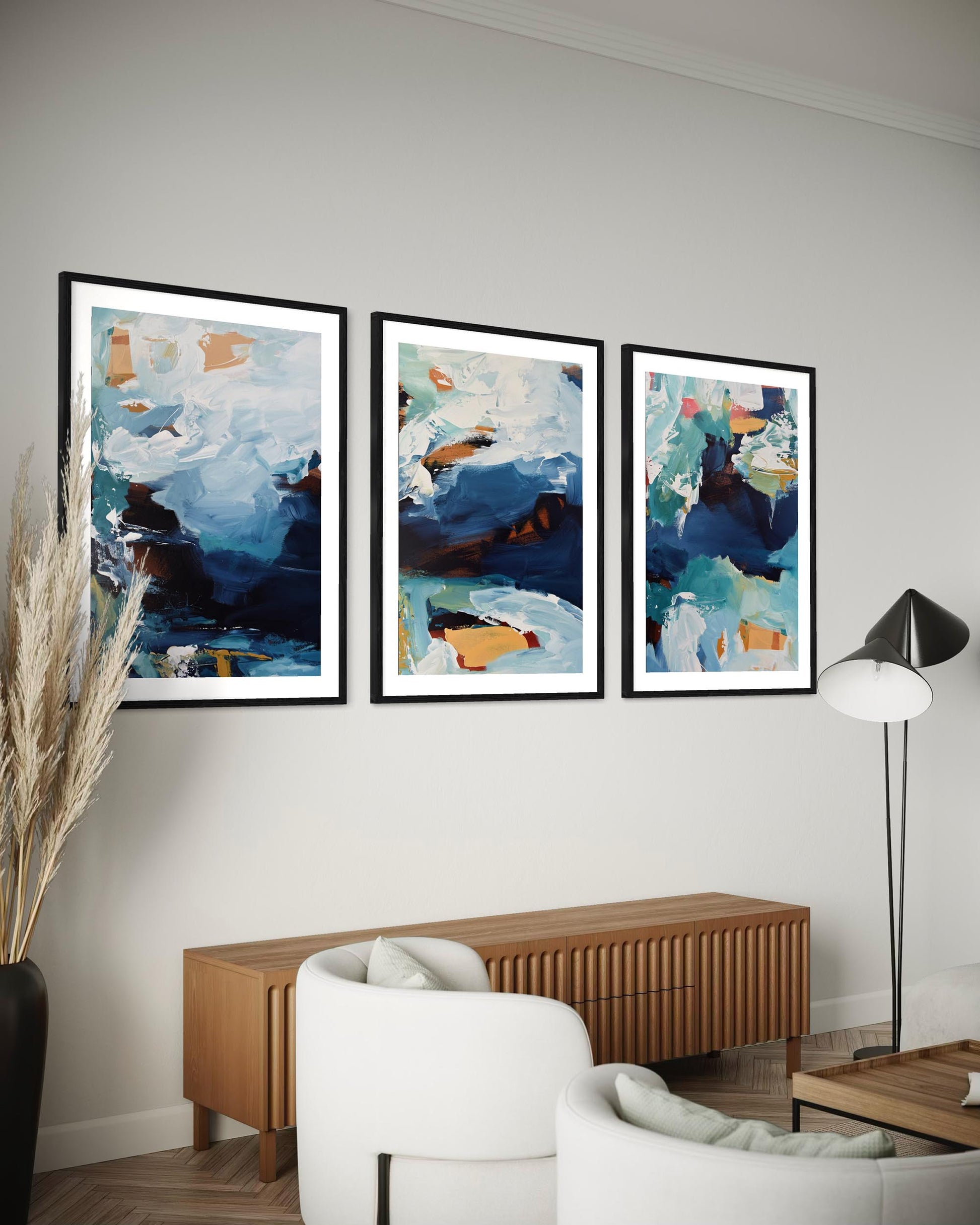 Three abstract paintings on a wall above a wooden console table in a living room.