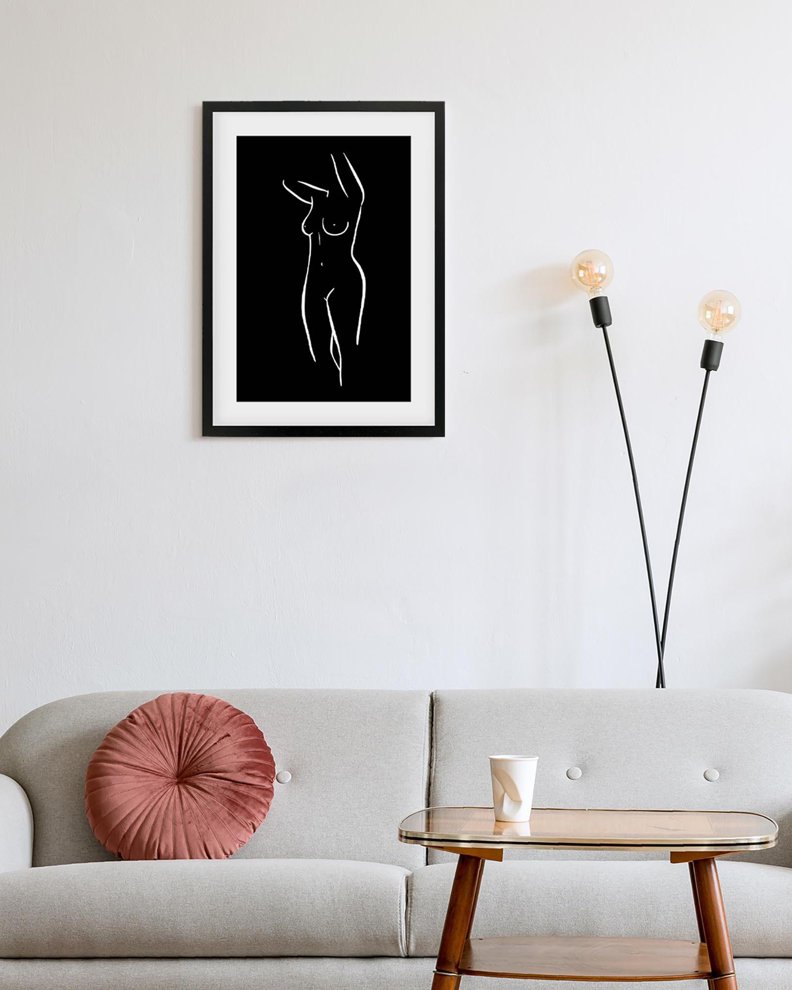 Framed black and white abstract art on a wall above a sofa with a pink pillow.