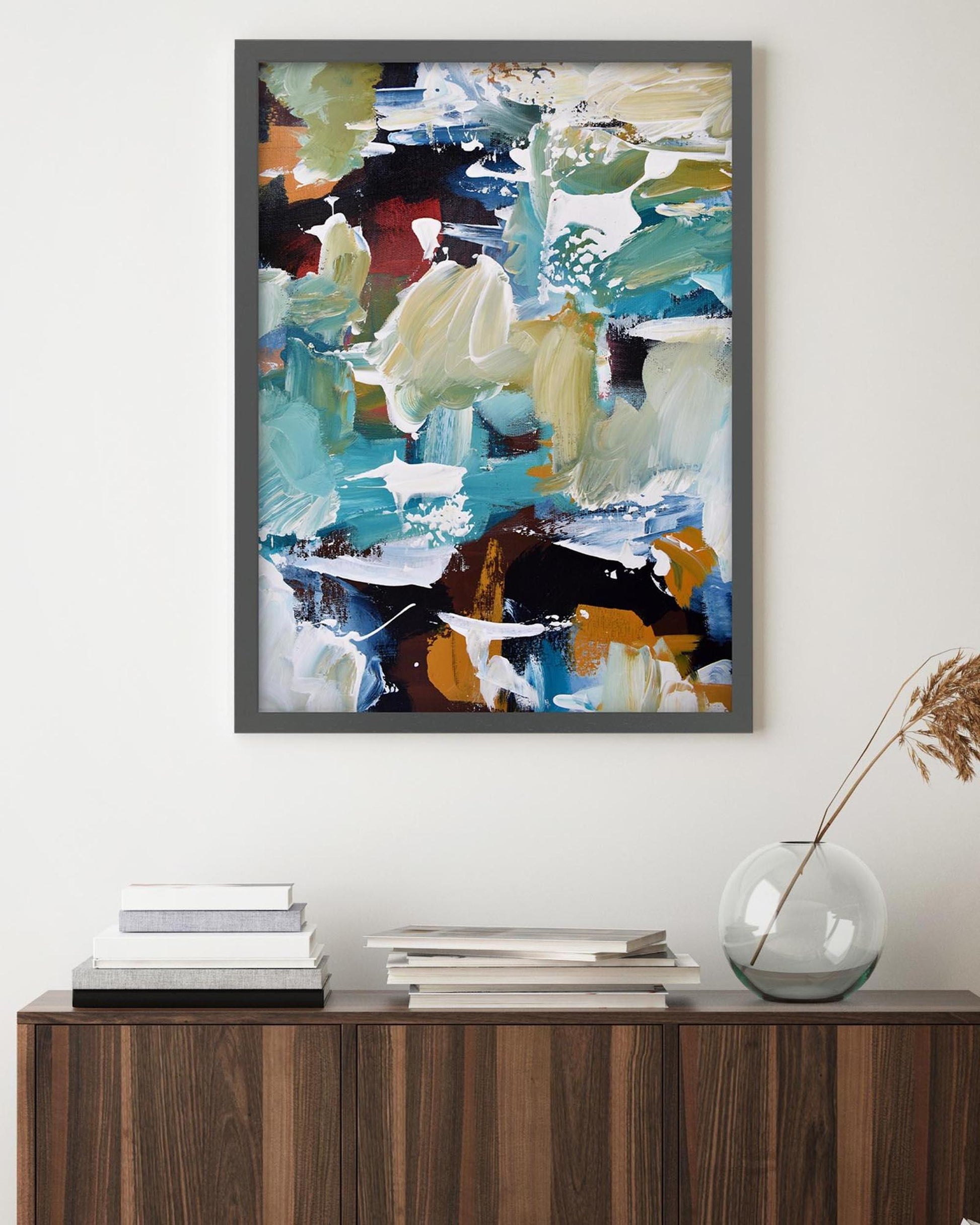 Abstract painting in a gray frame on a wall above a wooden console table.