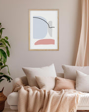 Abstract art print on a wall above a sofa with pillows and a blanket.