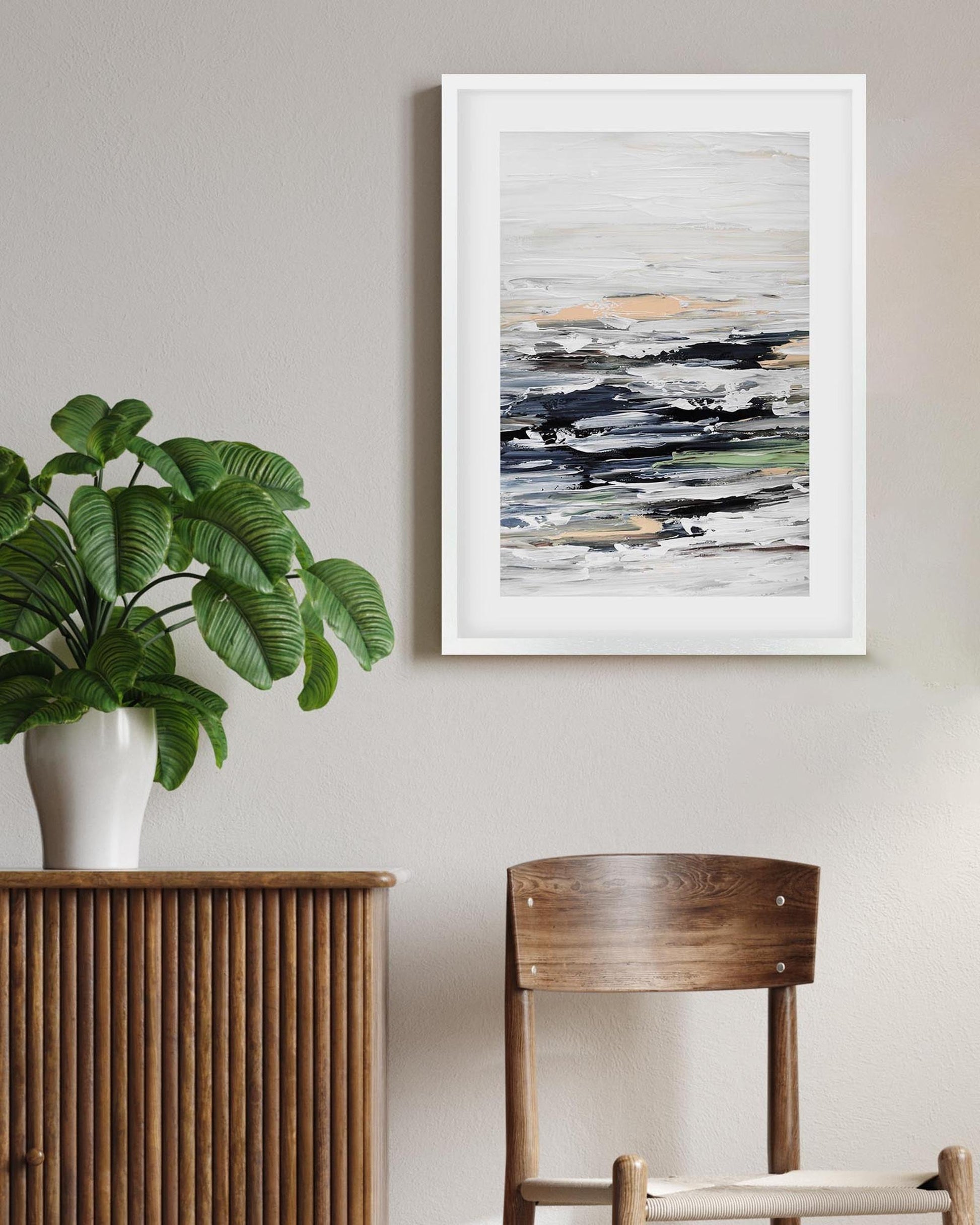 Room interior with a plant on a wooden sideboard, a chair, and abstract art on the wall.