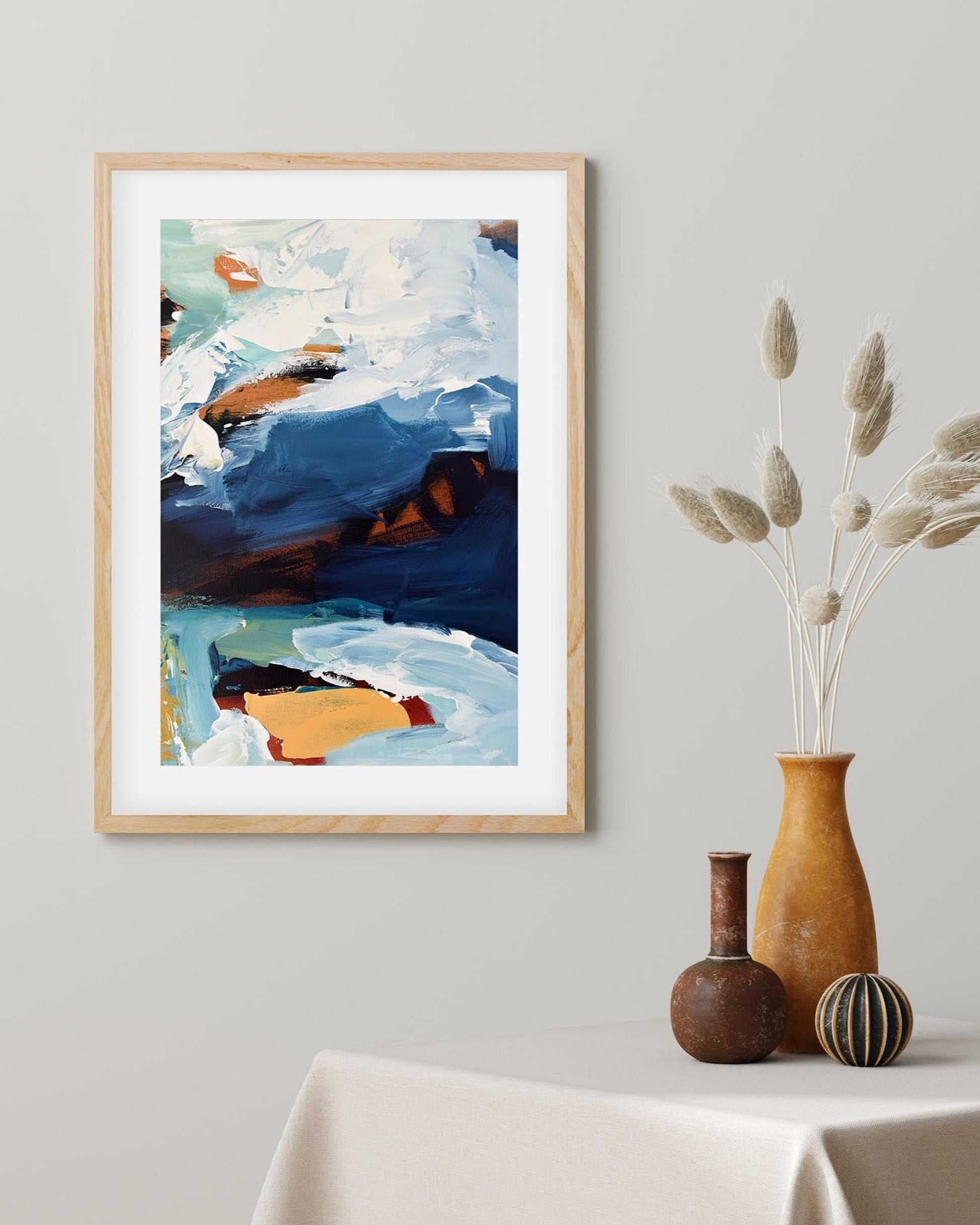 Framed abstract painting on a wall with decorative vases below.