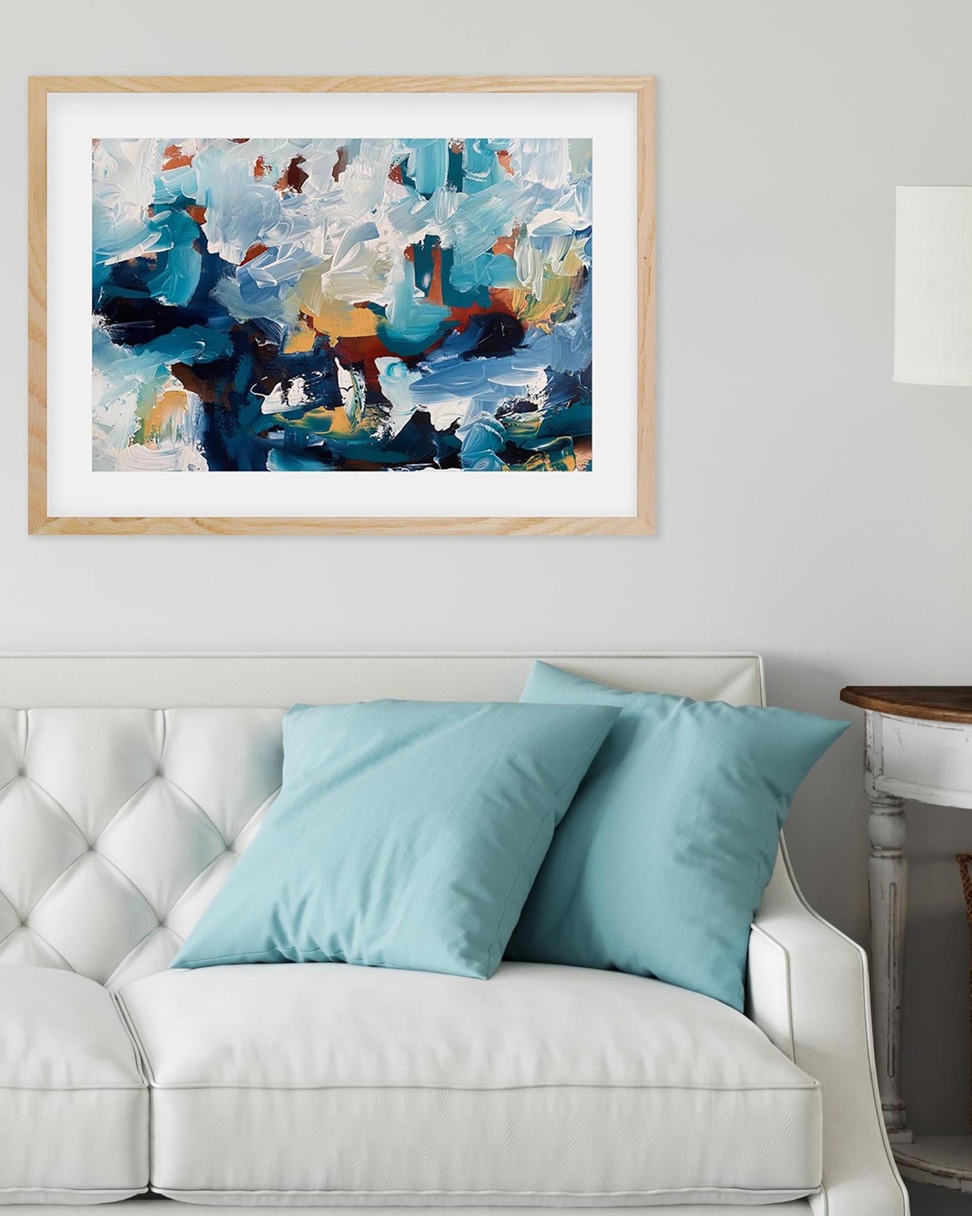 Framed abstract art above a white sofa with blue cushions